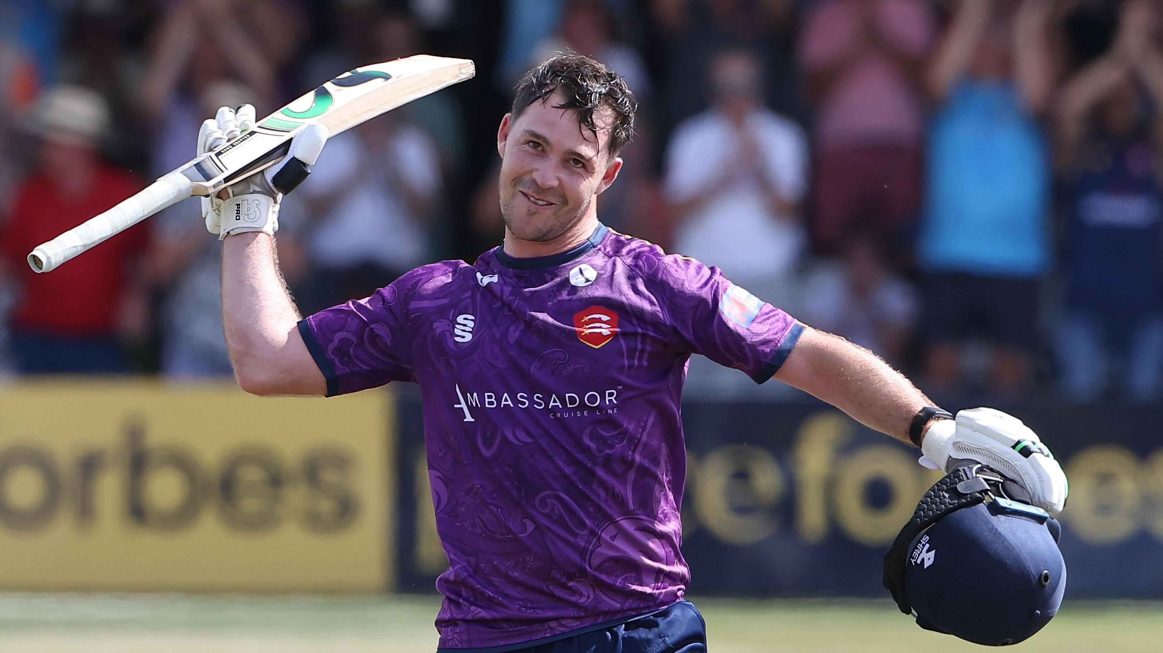 Curtis Campher, with his helmet off, raises his bat to acknowledge his century for Essex