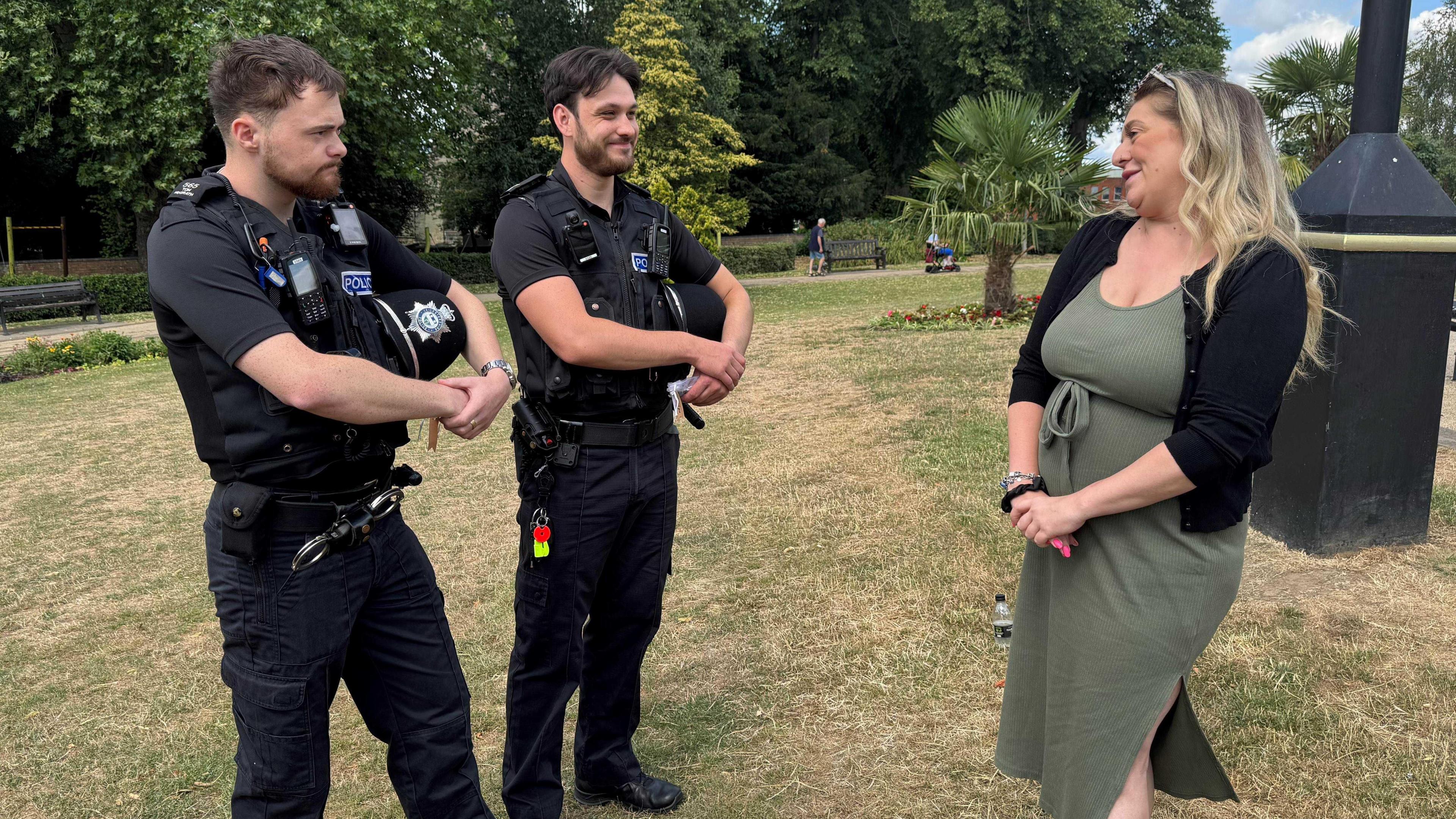 The two officers stand in their uniform in the park talking to Laura