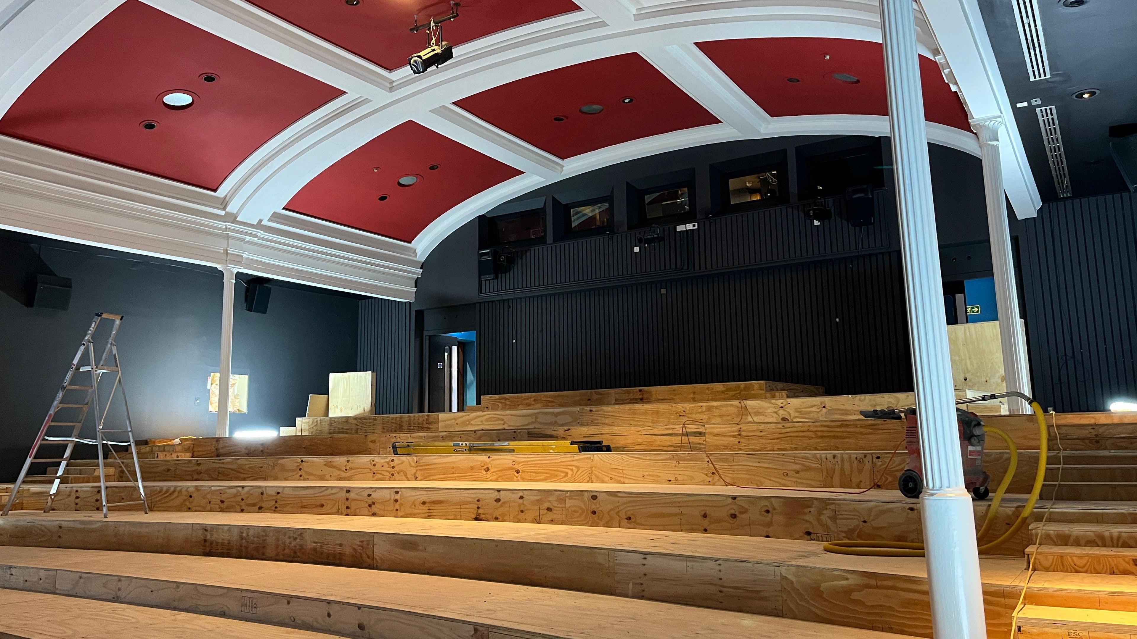 An image of work in progress on one of the Filmhouse's screens. The seats have been removed and se see the tiered levels. There are work materials around the area.