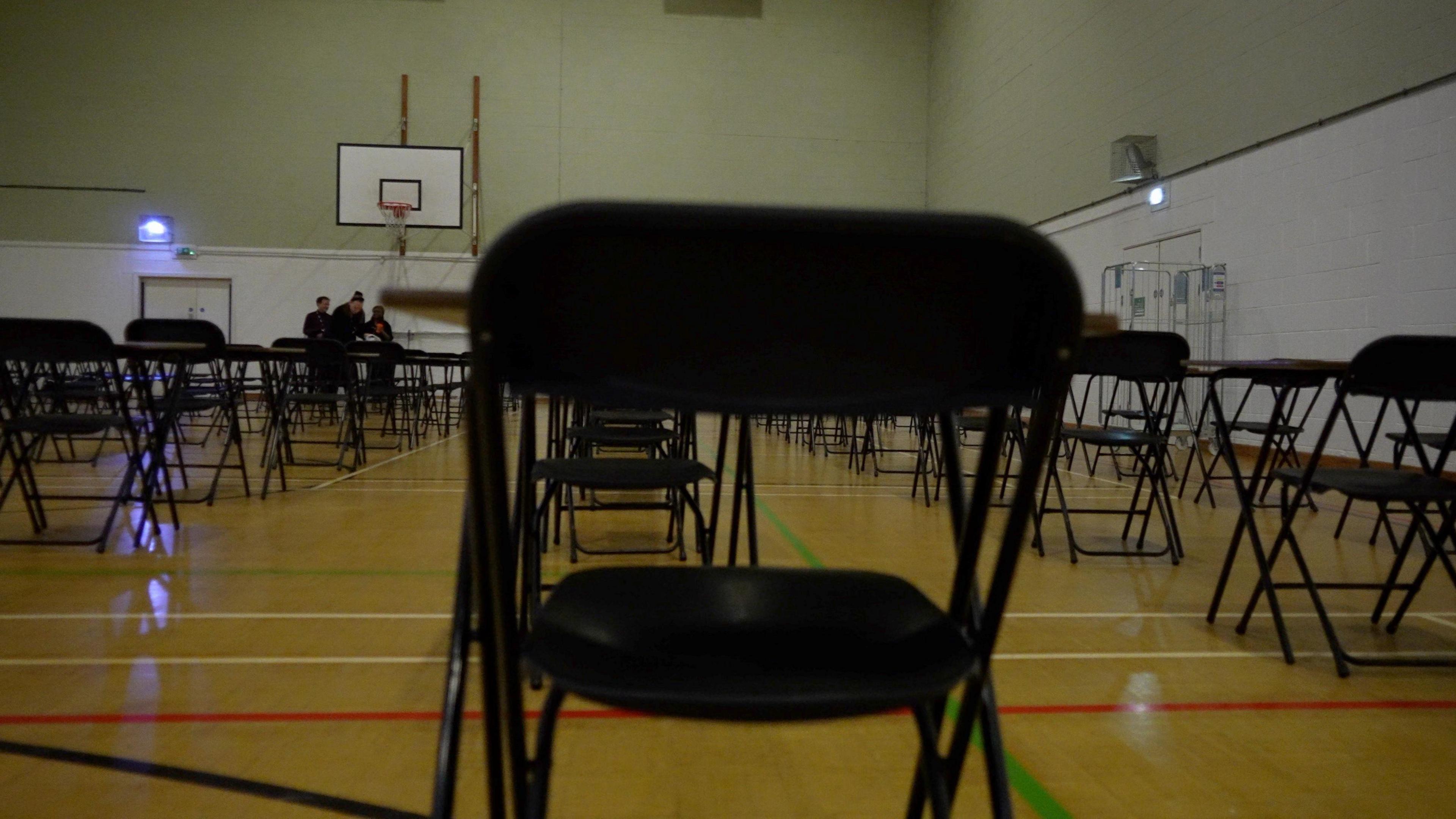 A sports hall, with tables and chairs set up for an exam