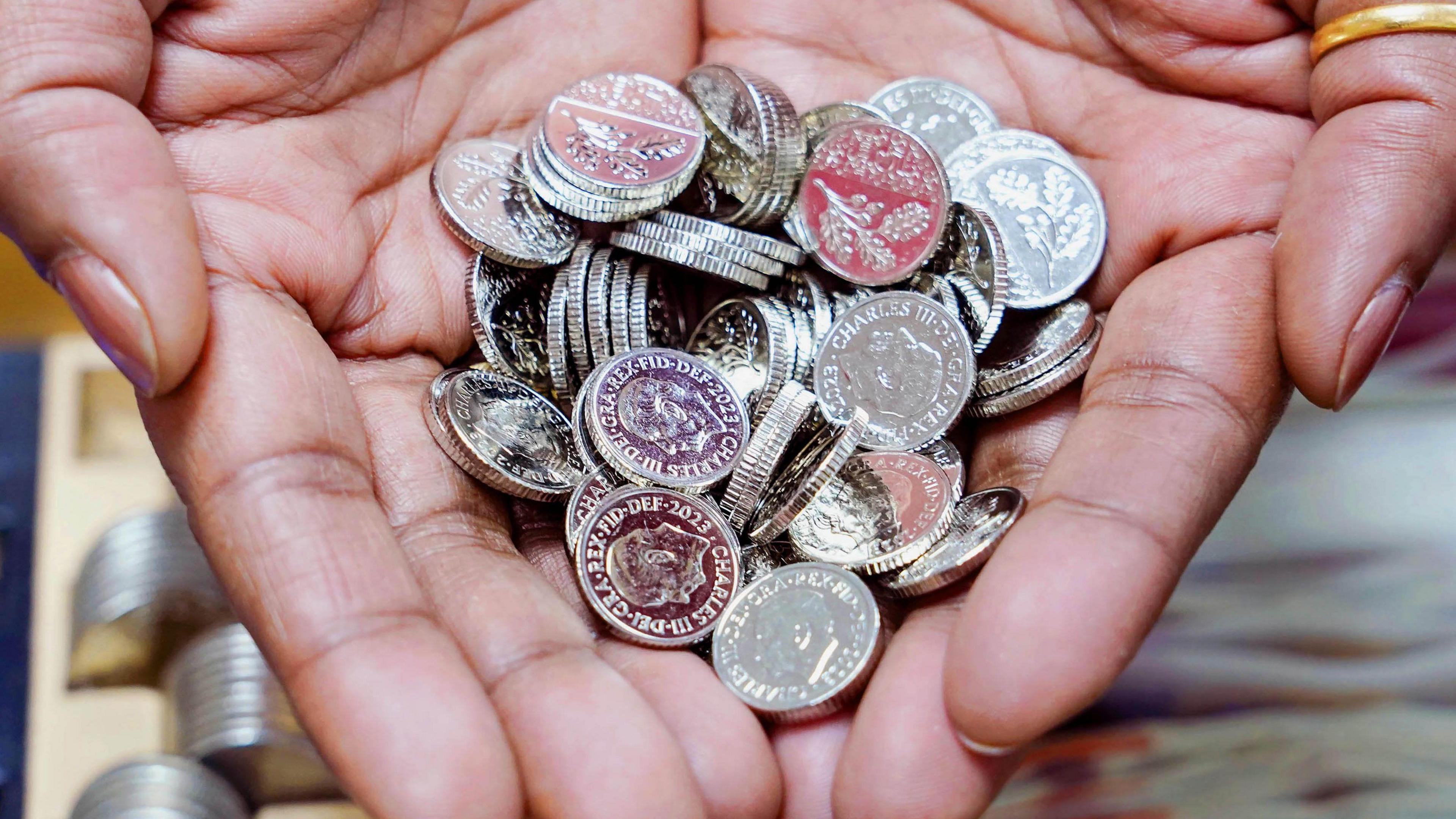 a lady holding a collection of the new 5p coins in her hands