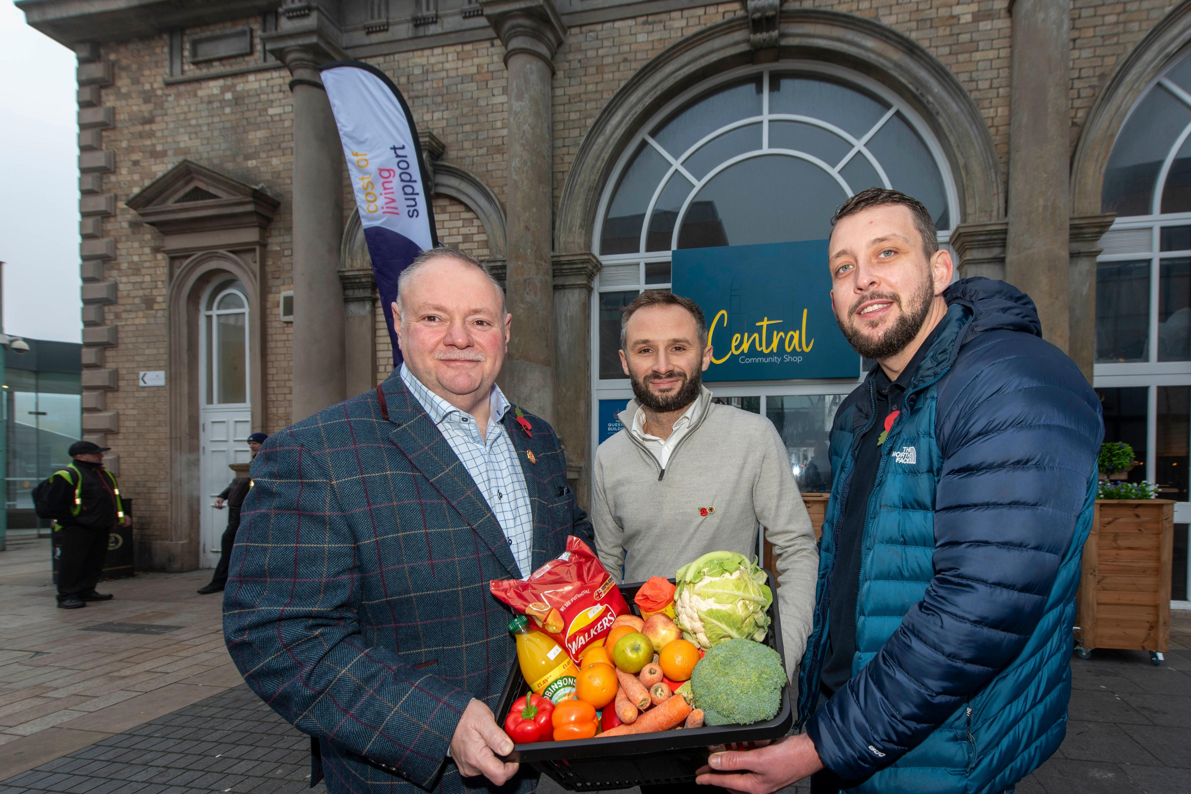 Three men hold a box of food outside the Queen's Building in Wolverhampton