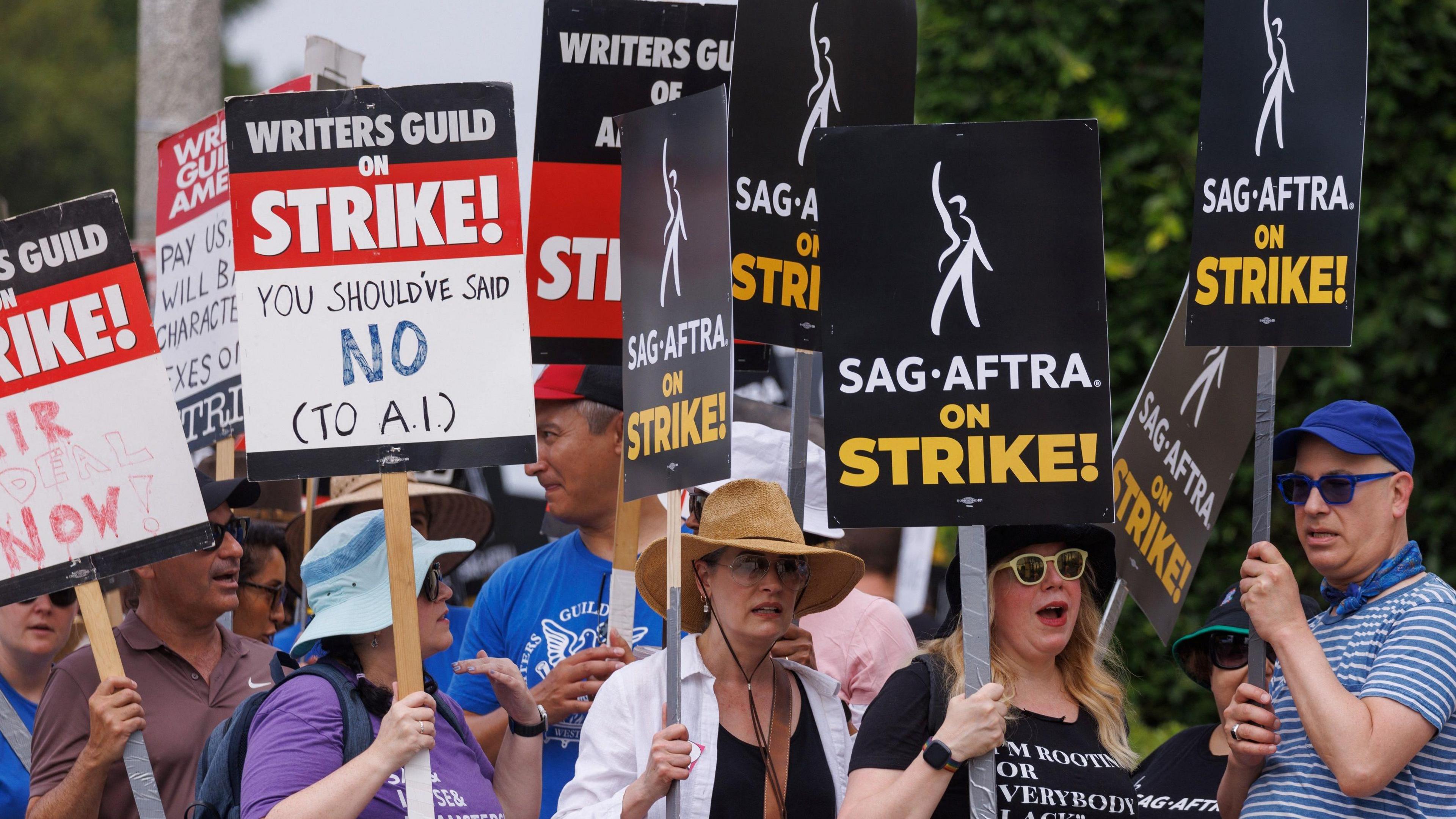 Members of the Hollywood's actors and writers unions walk with signs in Los Angeles, California. They wave signs that say "On Strike" and others blasting AI. 