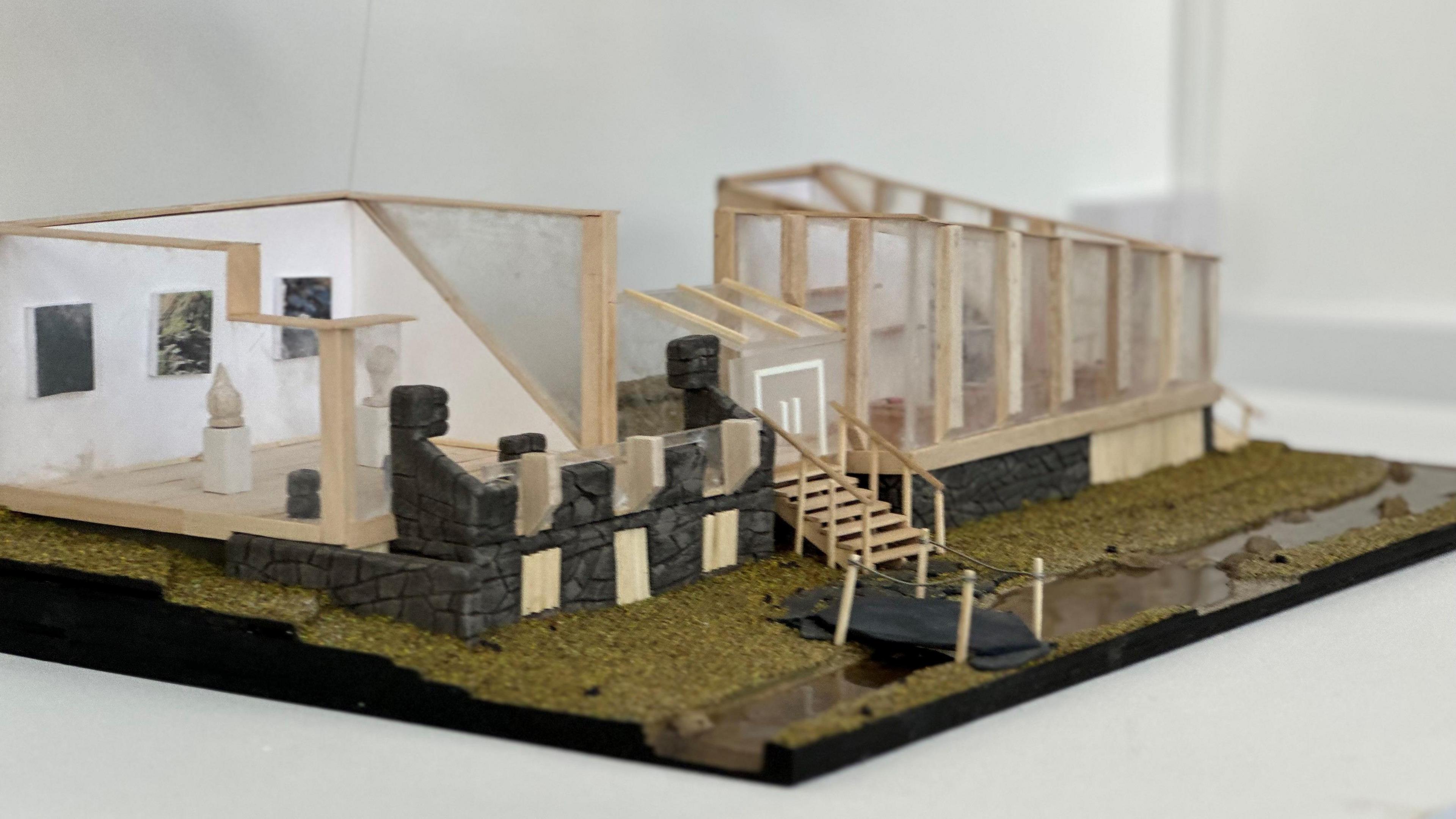 A model of a renovated tholtan made of pieces of wood, with some painted to look like stone.