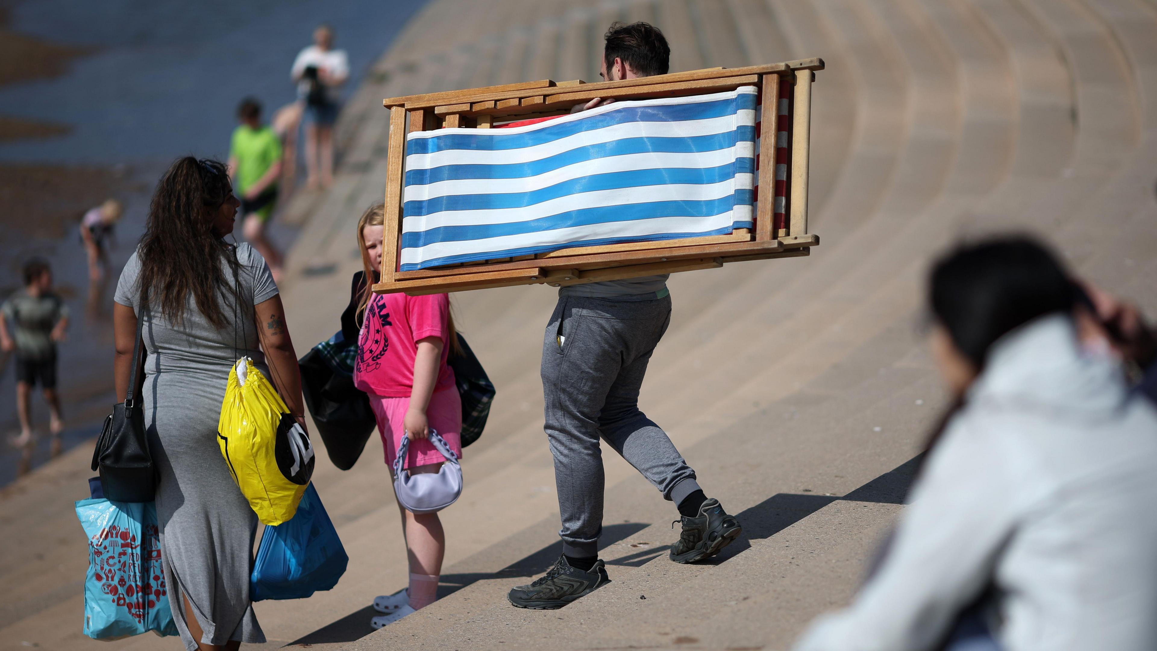 A man carrying a deckchair on Blackpool beach