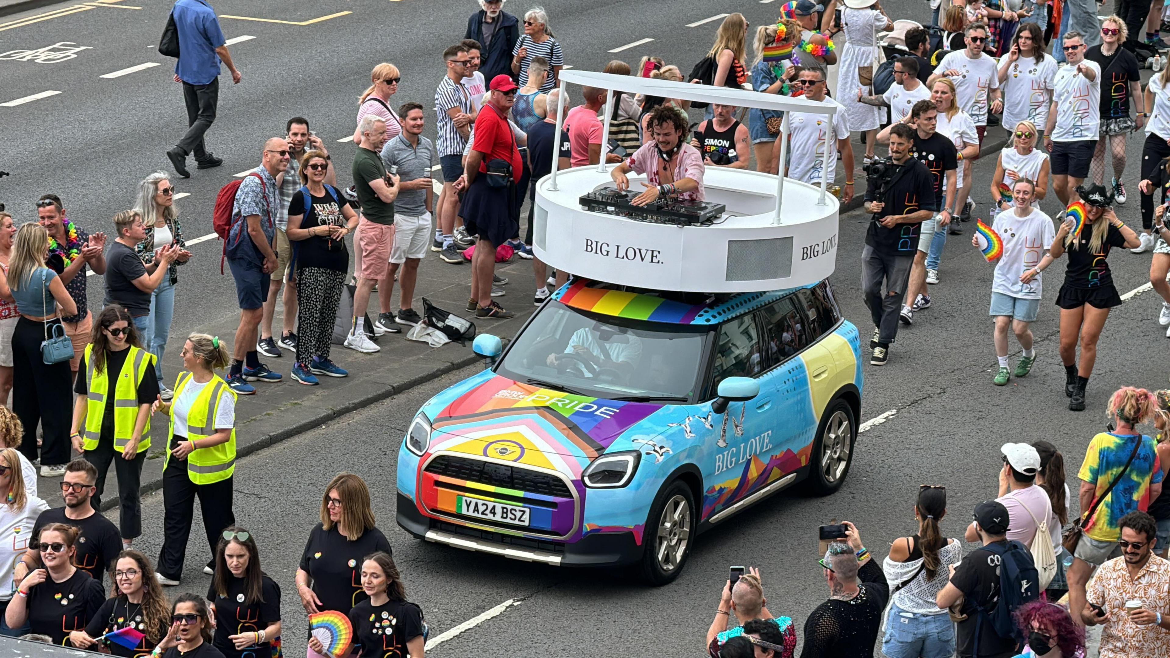 DJ Woody Cook on the roof of a rainbow Mini in the Brighton Pride parade