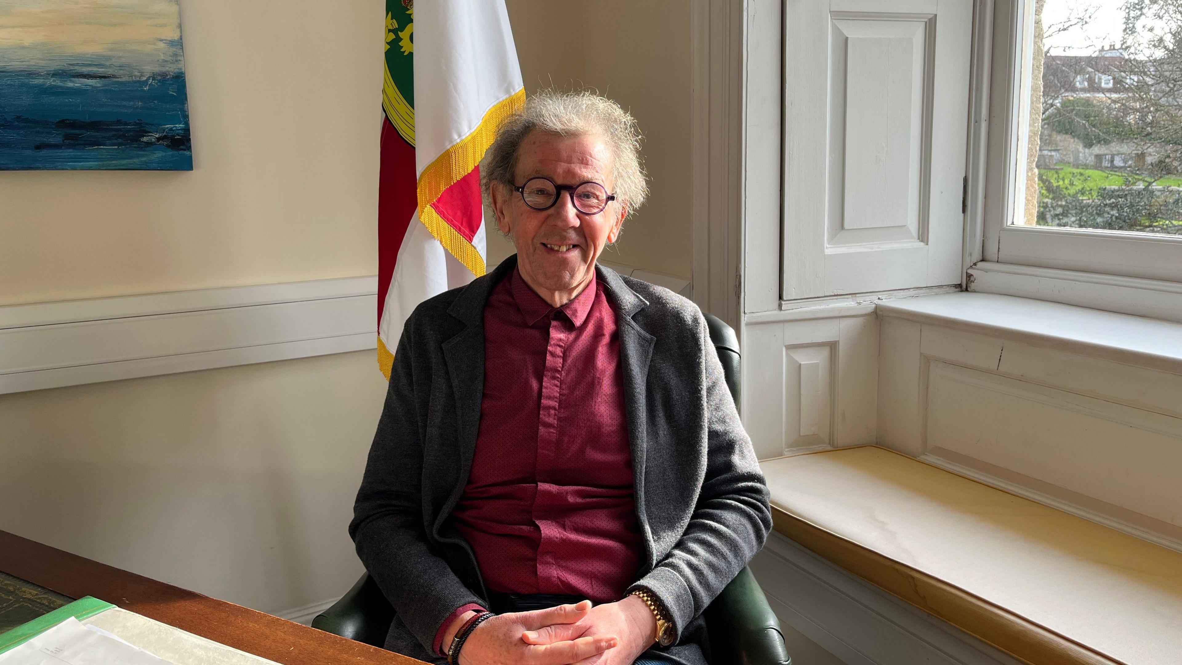 President William Tate, sitting at a desk and smiling at the camera