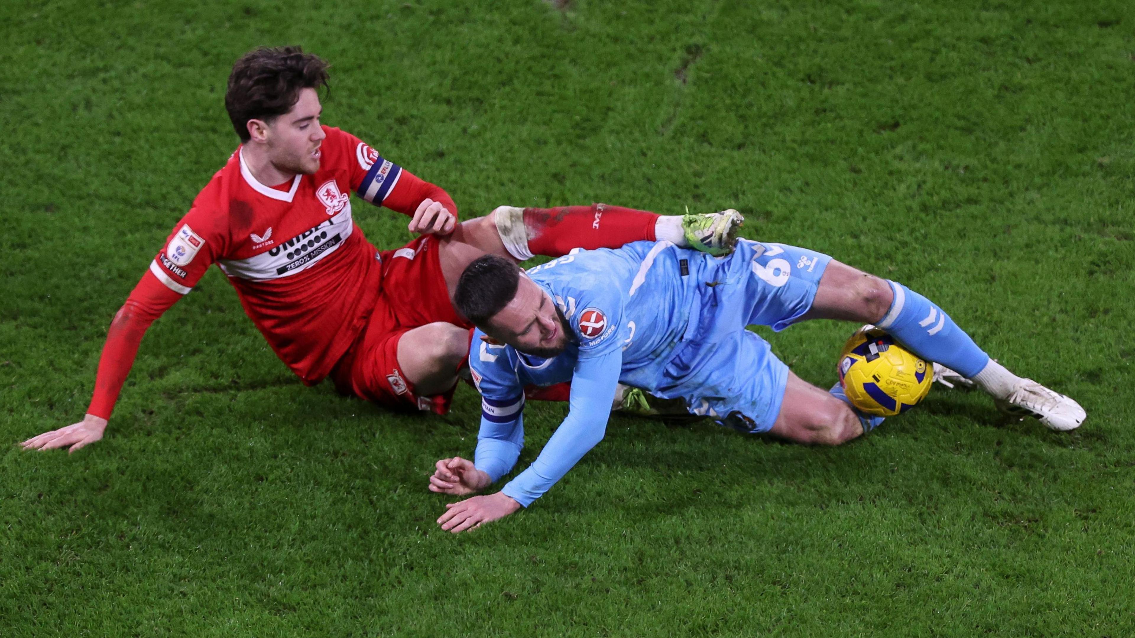 Hayden Hackney (left) and Matt Grimes are on the floor but the Coventry player has the ball between his legs