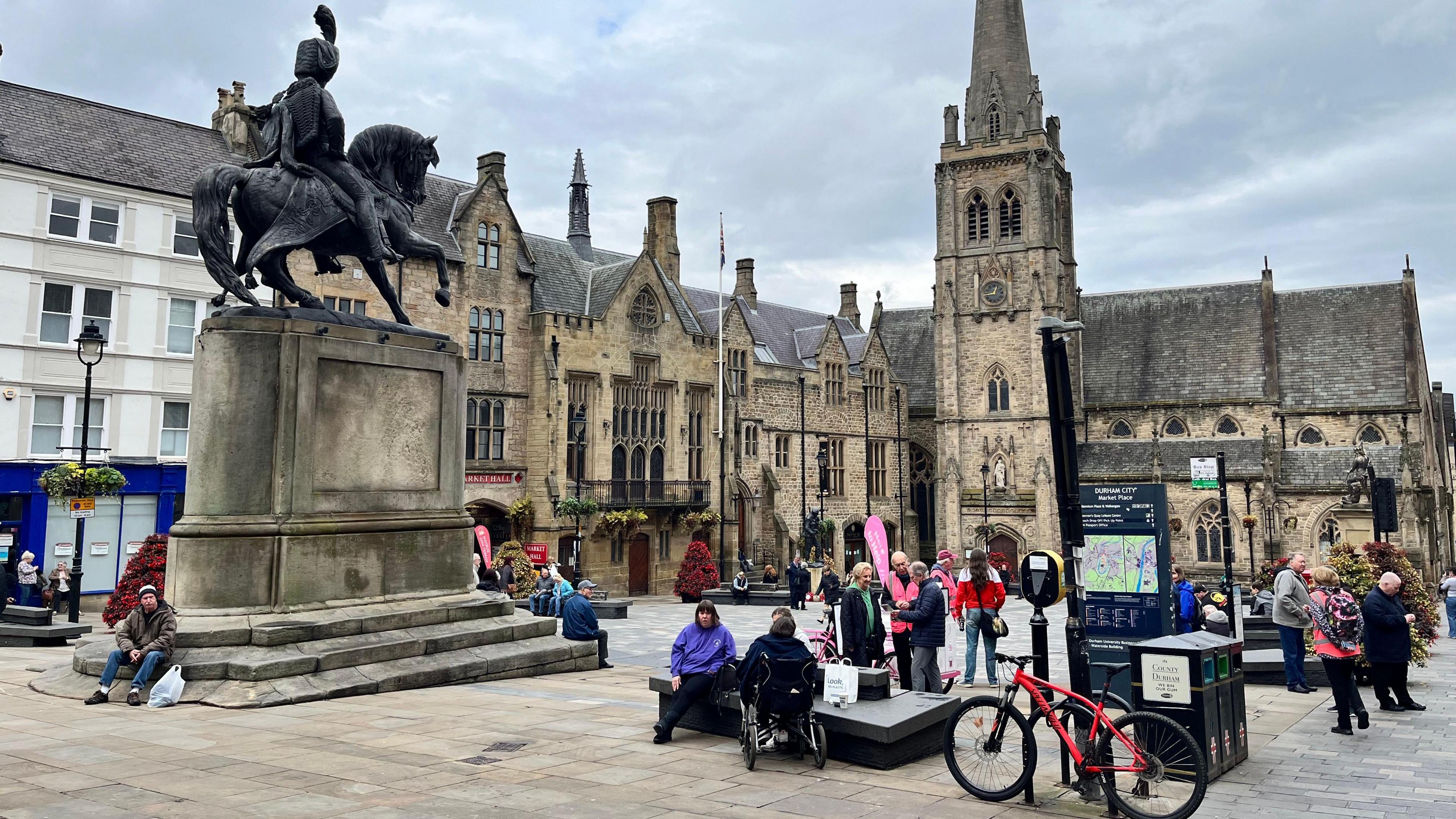 A general view of the Market Place in Durham city centre. There are a few people sitting on the monument steps.