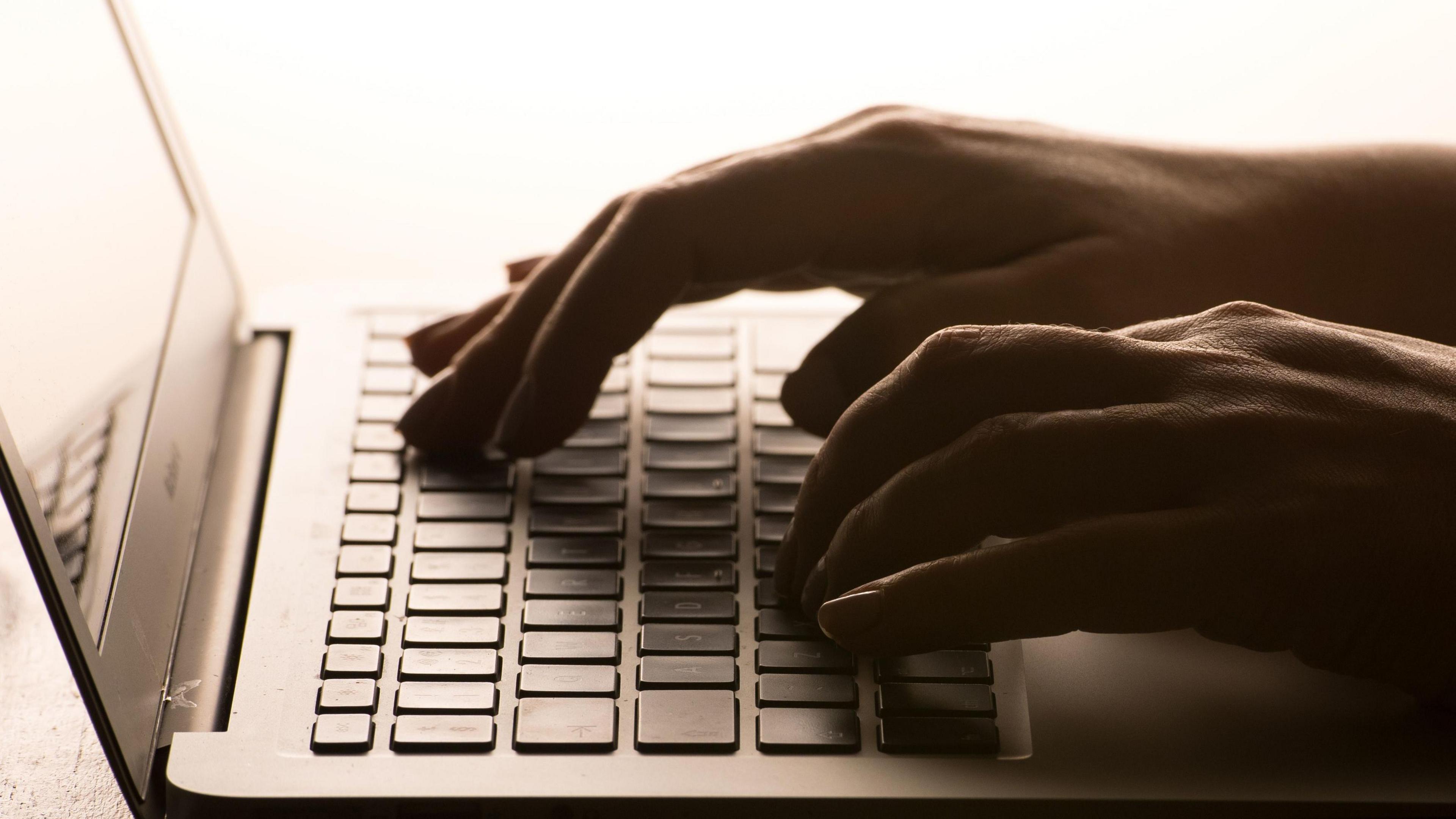 Hands typing on a laptop keyboard.