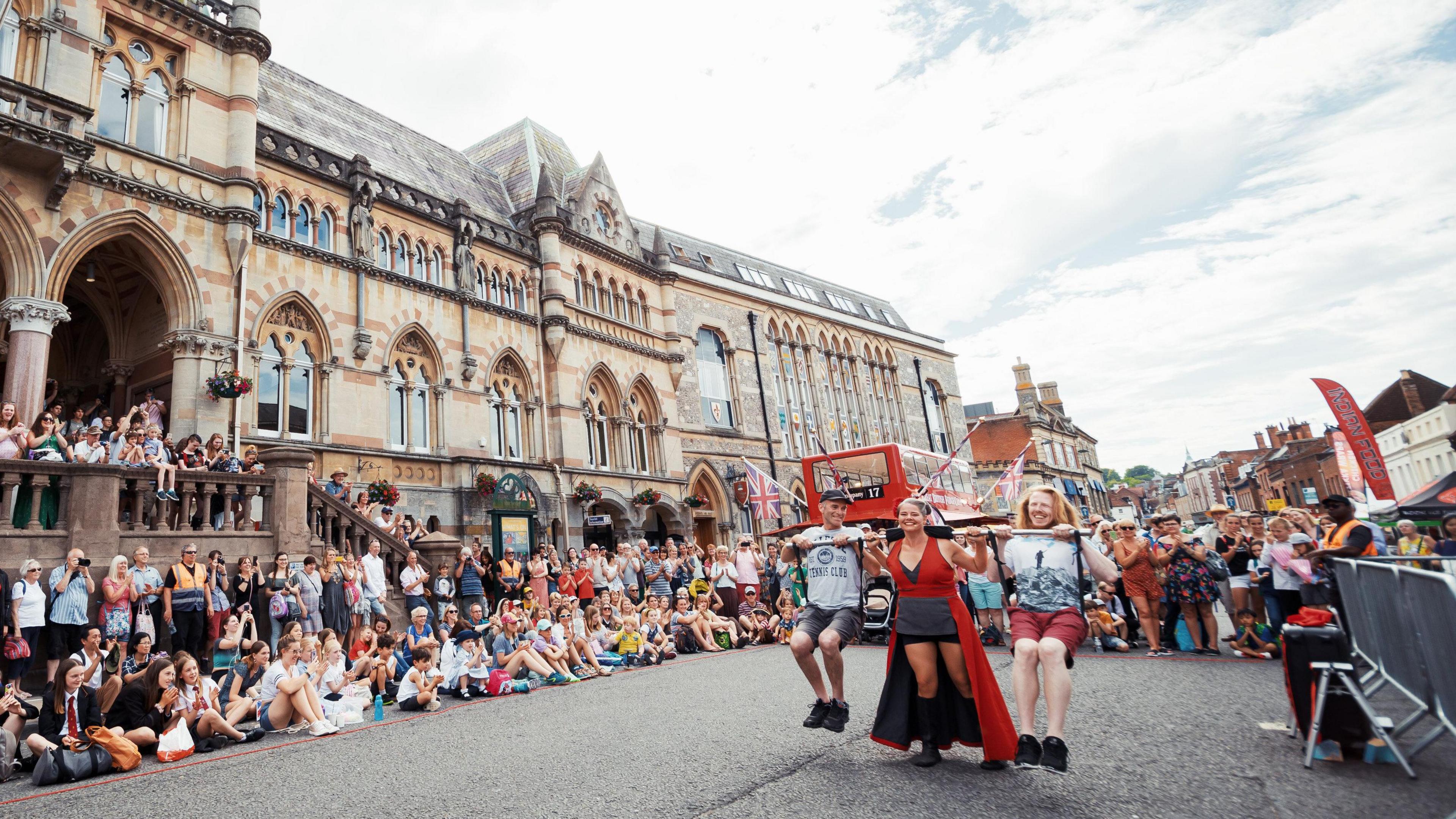 Arts performers in the streets of Winchester surrounded by an audience of people watching them