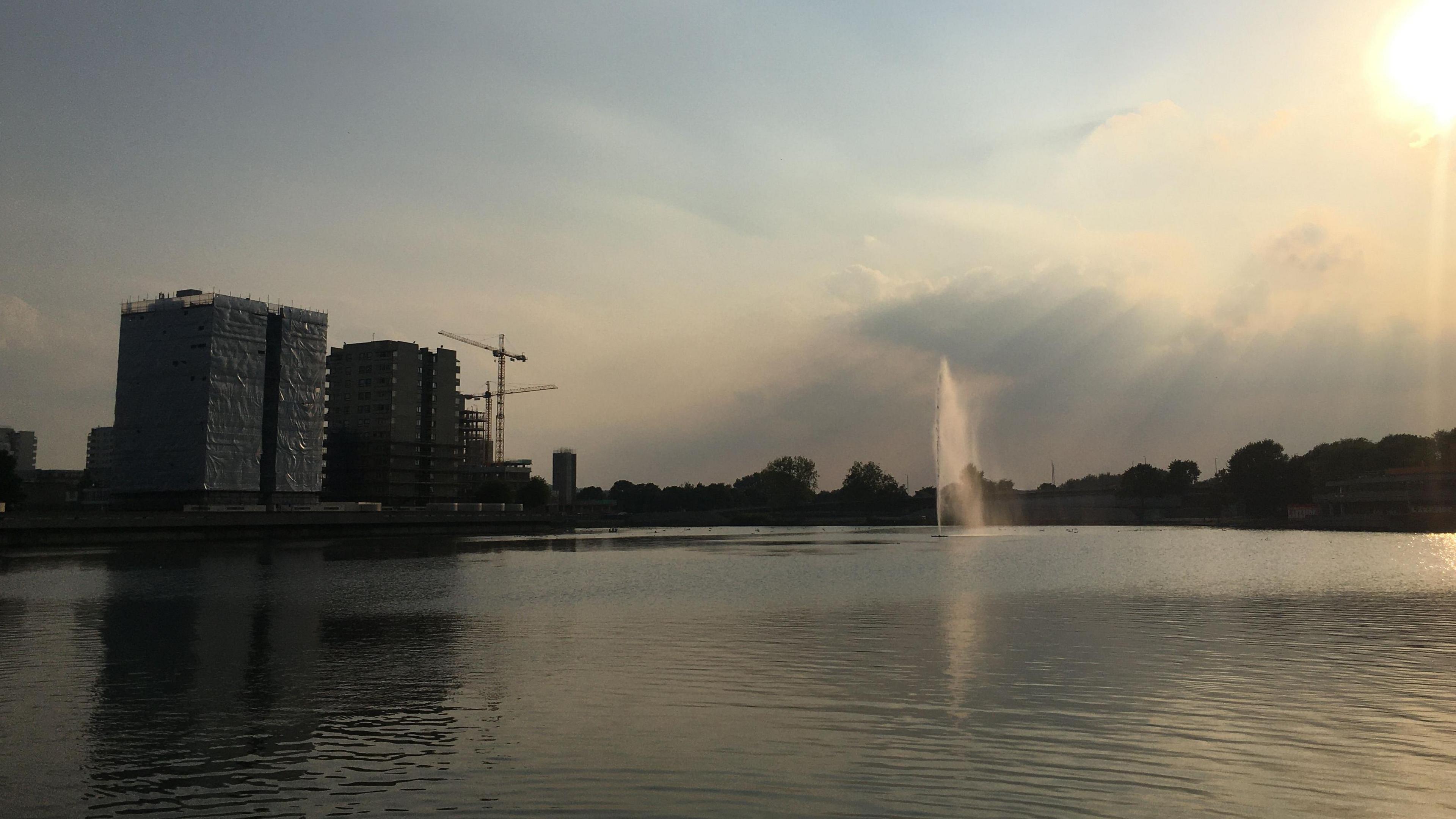 Southmere Lake on a sunny day with tower blocks and a crane in the background.