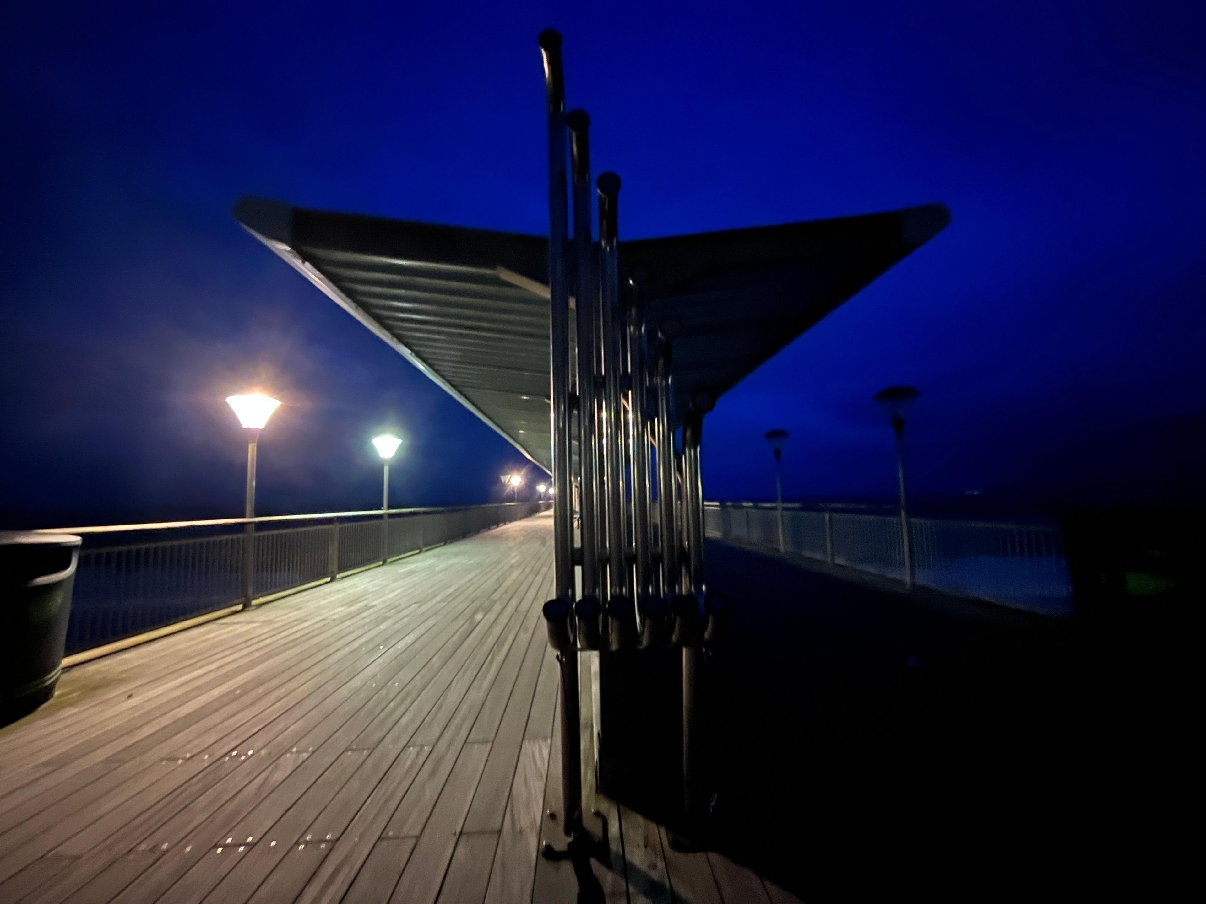 A shelter on a pier; one side is lit, the other in darkness