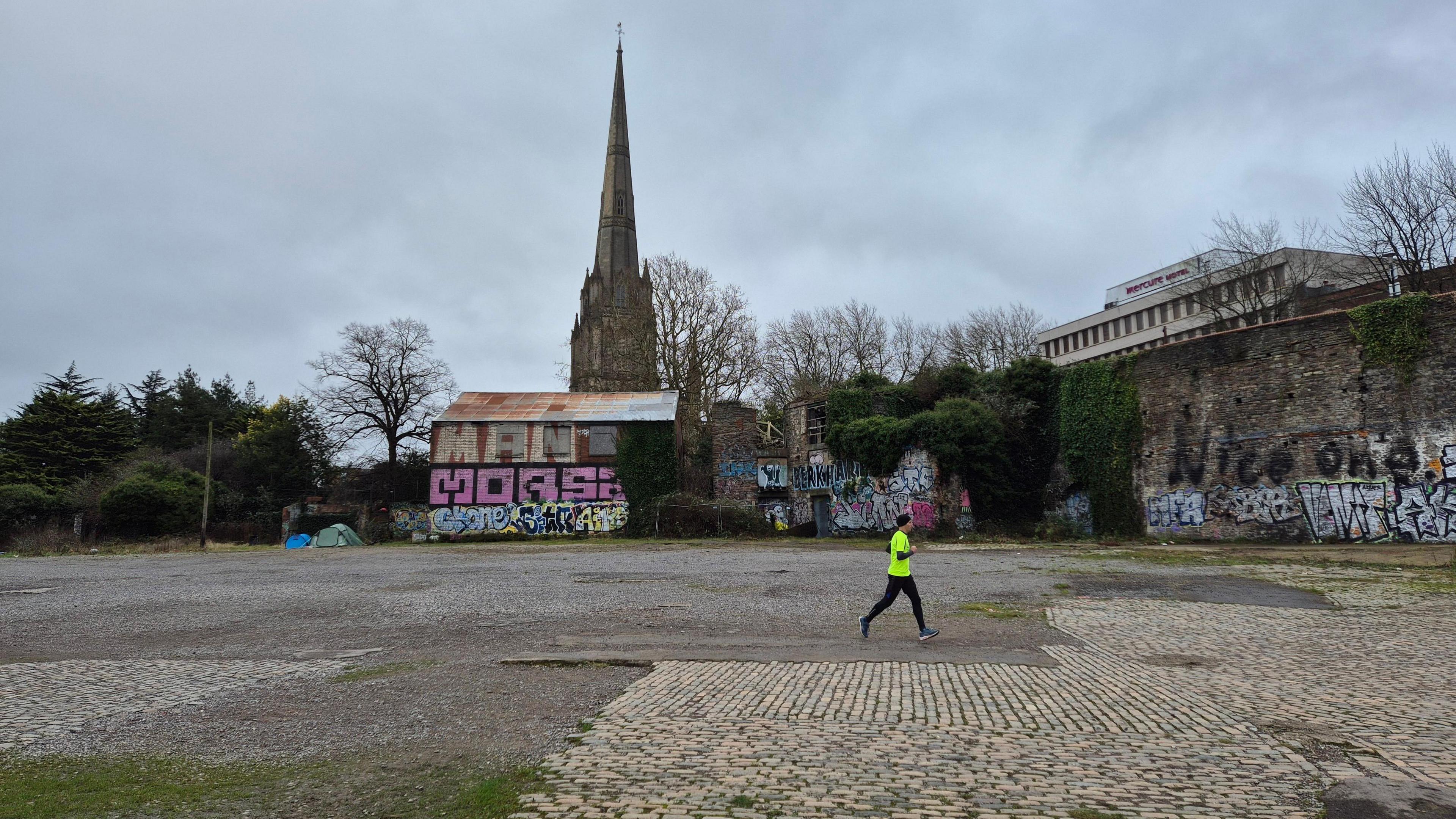 Redcliffe Wharf covered in graffiti with a person wearing a flourescent top running past