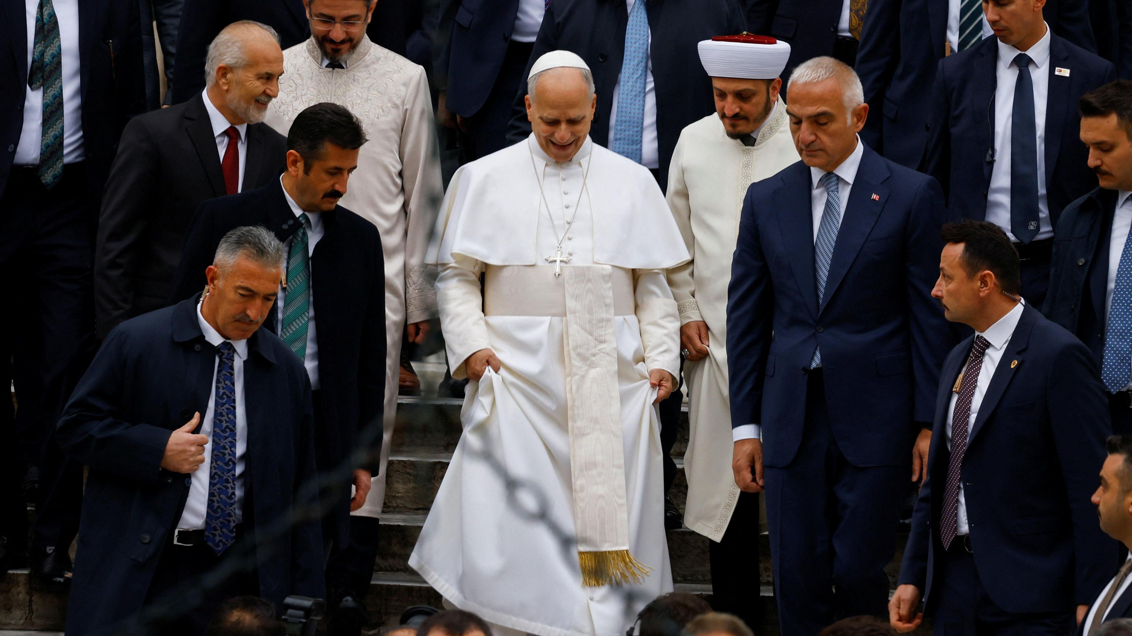 Pope Leo, draped in white robes, descends the steps of the Blue Mosque.