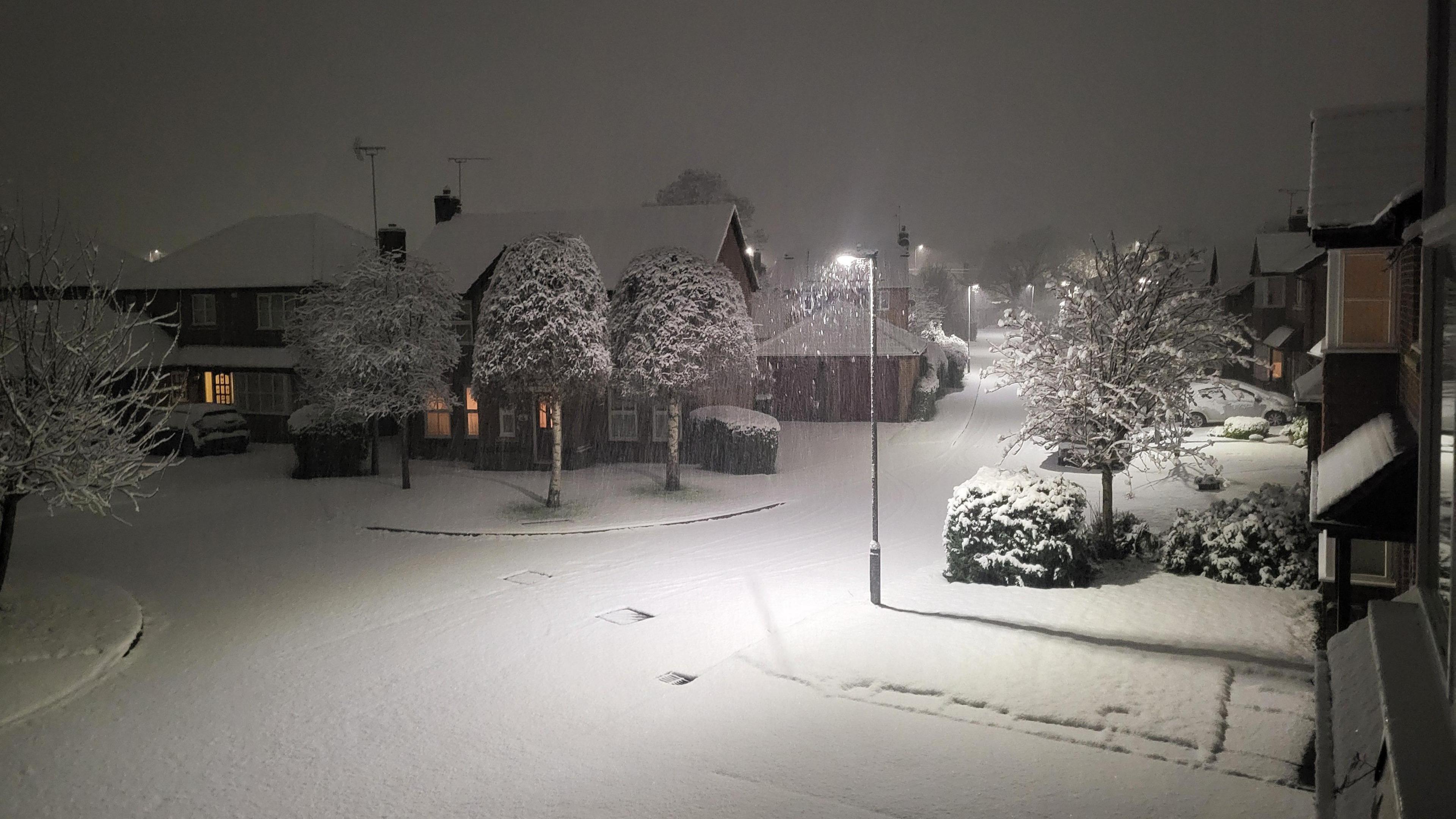 An estate in the night time illuminated by streetlights. Snow covers everything. 