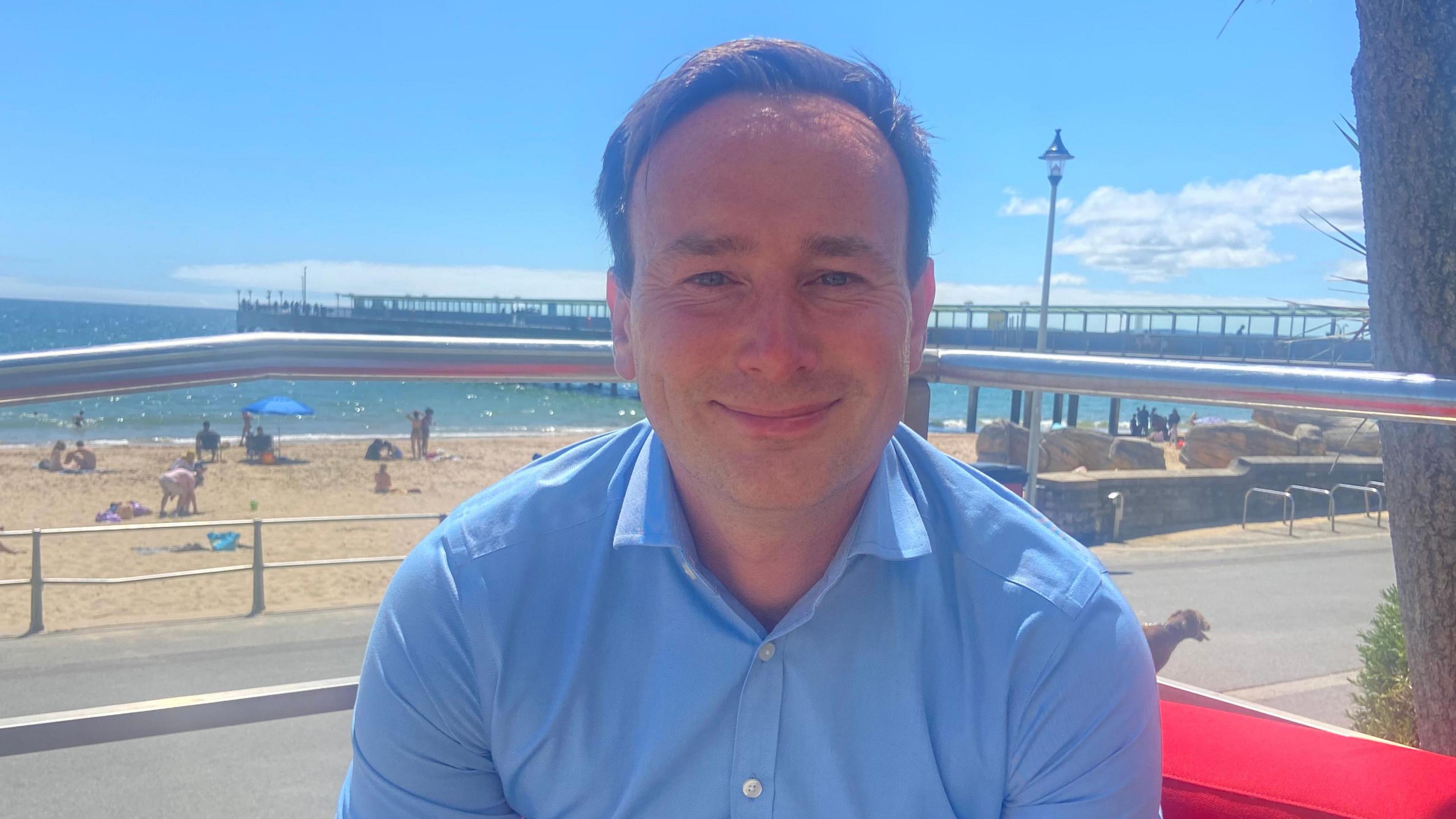 Labour's Tom Hayes wears a blue shirt while sitting on the red sofa