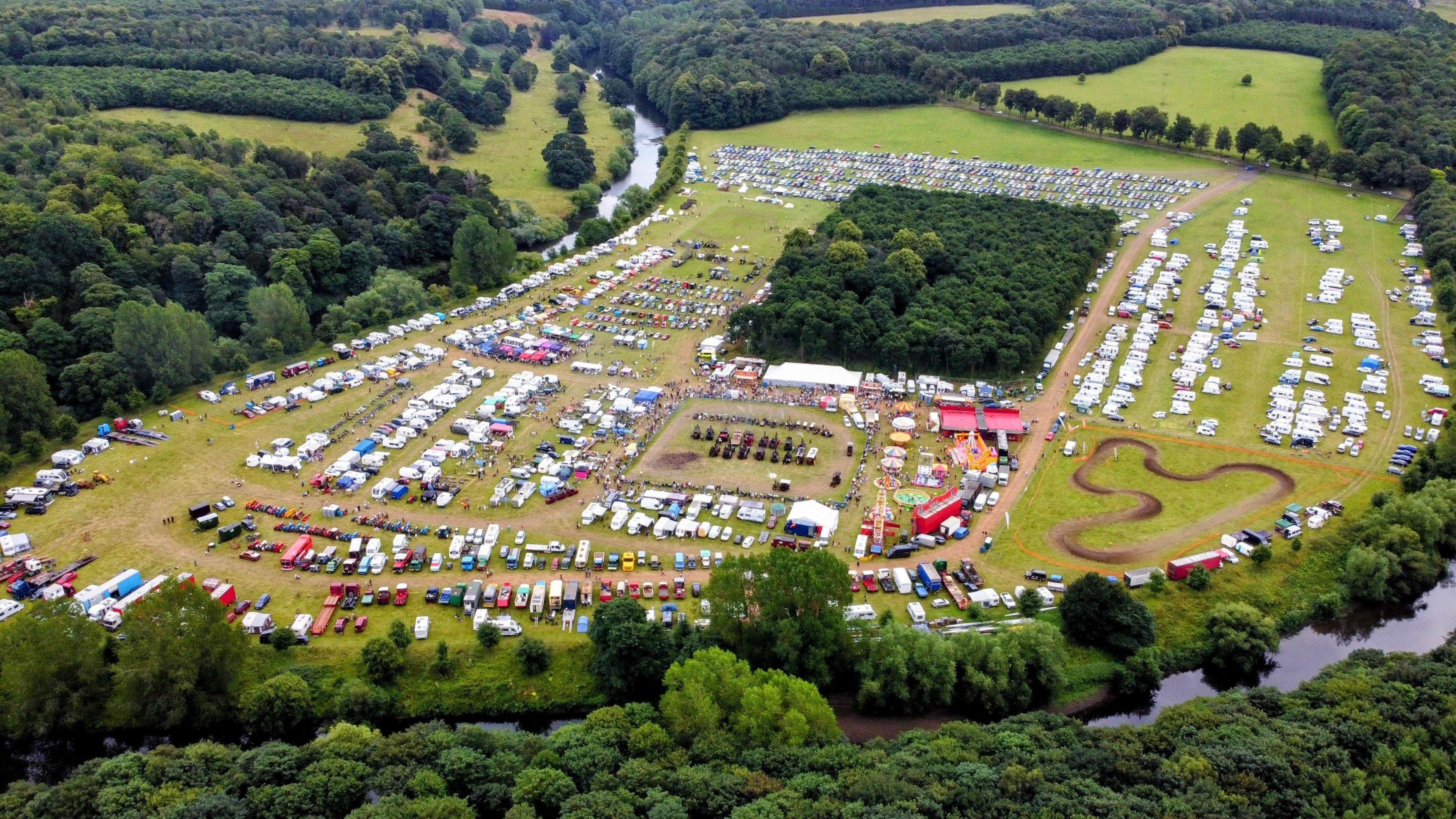 Aerial view of a fair showing vehicles lined up and fairground rides