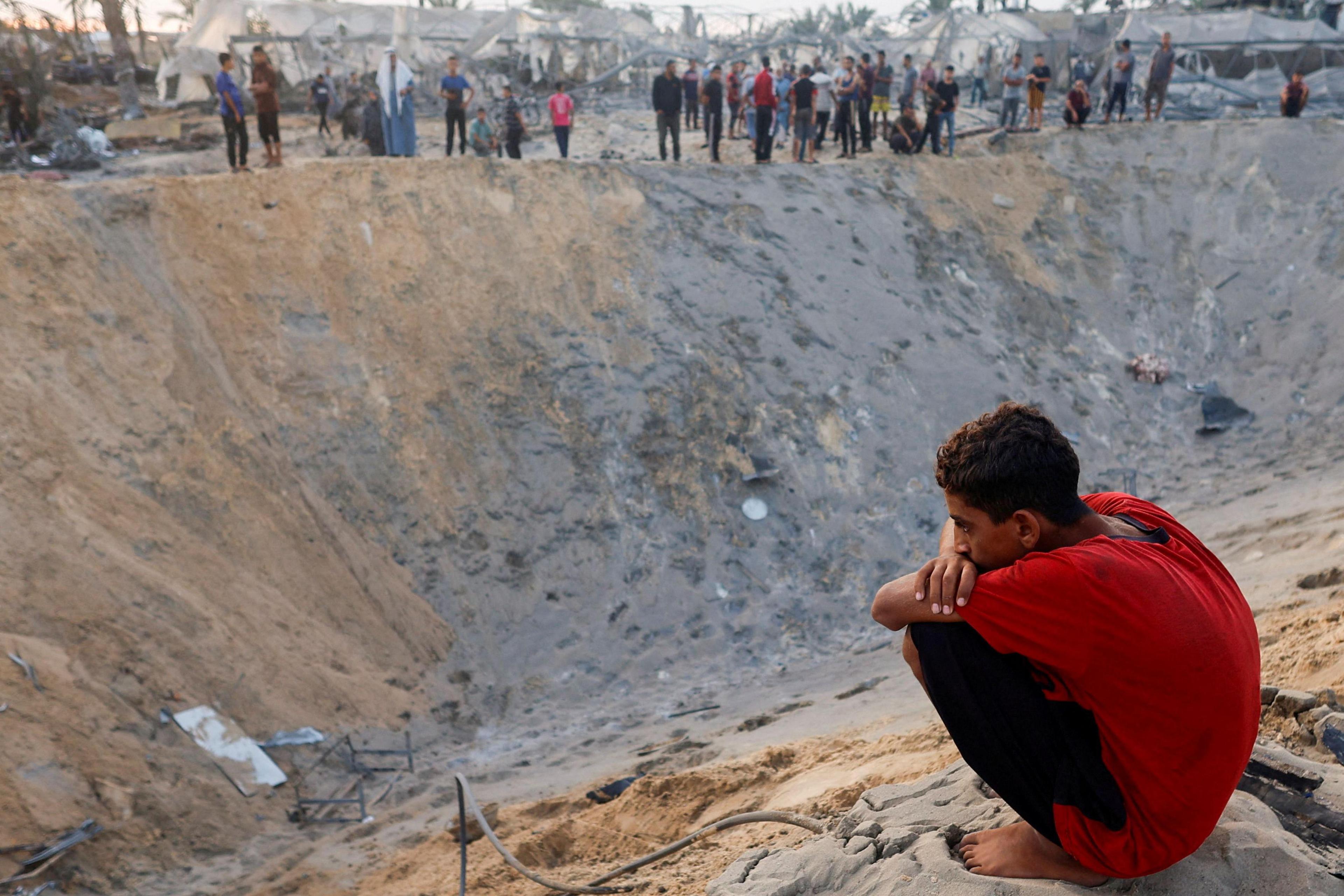 Palestinians stand next to a crater left after an Israeli air strike in the al-Mawasi humanitarian zone in southern Gaza (10 September 2024)