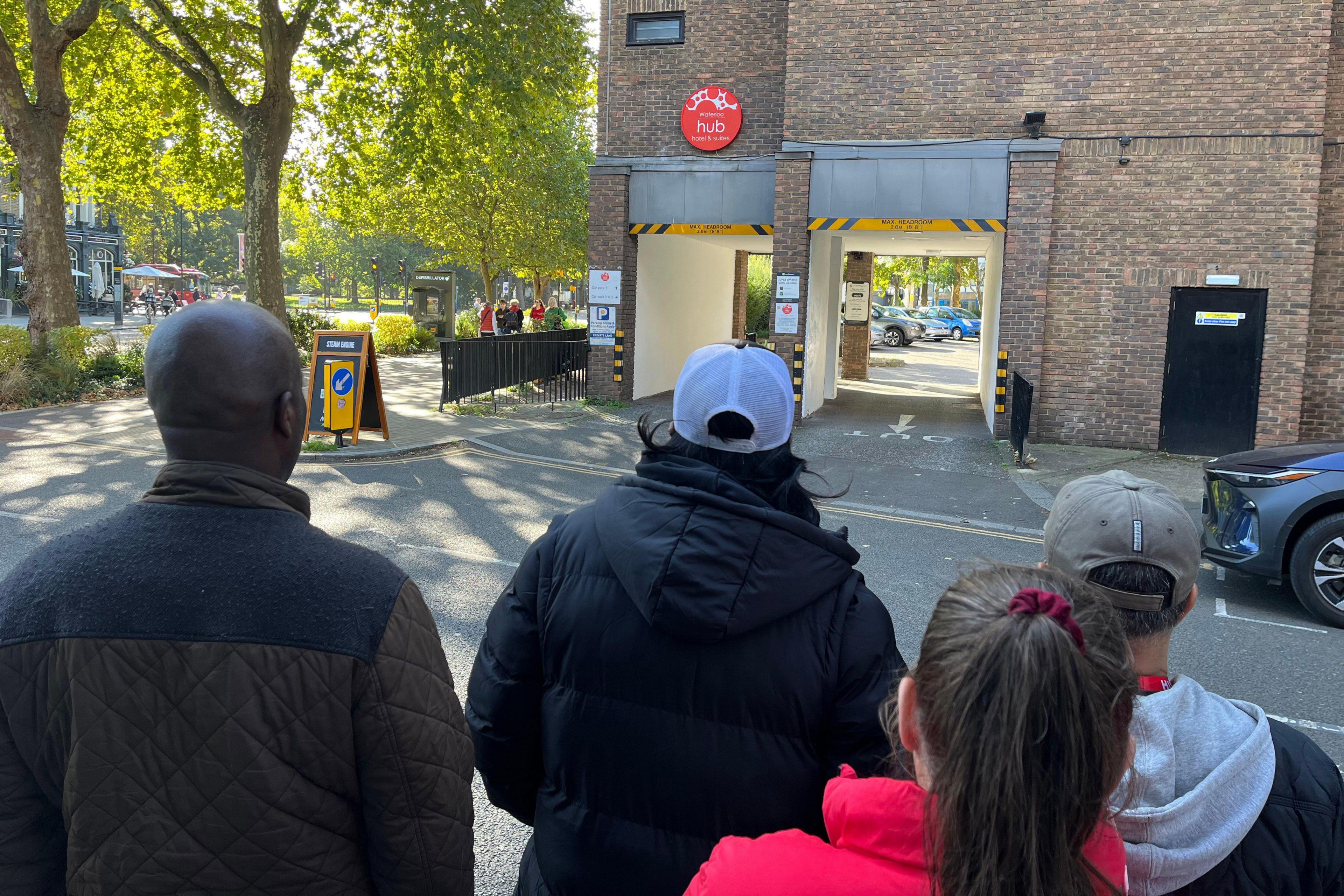 The back of the heads of four residents facing a brick building