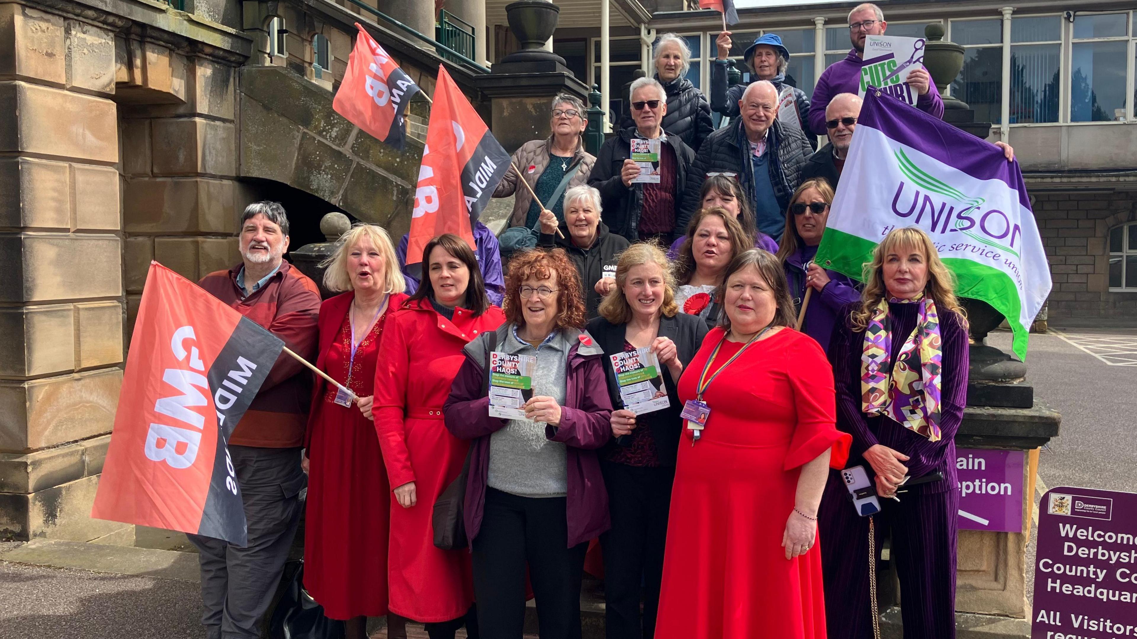 Labour councillors and union campaigners gather on the steps of Matlock County Hall waving flags in a rally in support of the care homes and day centres under threat