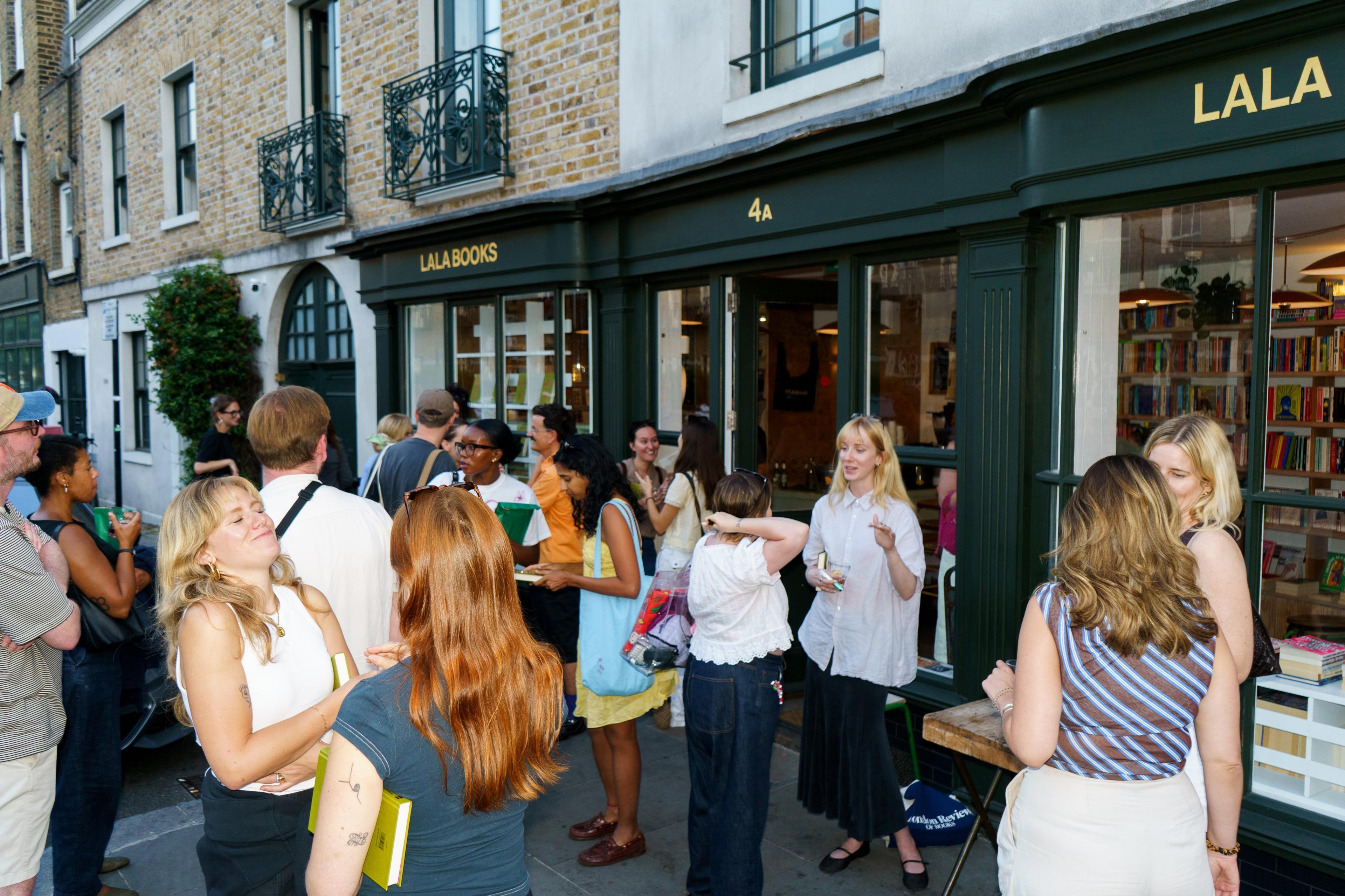 People standing outside a shop with green awning and the lettering 'Lala Books'