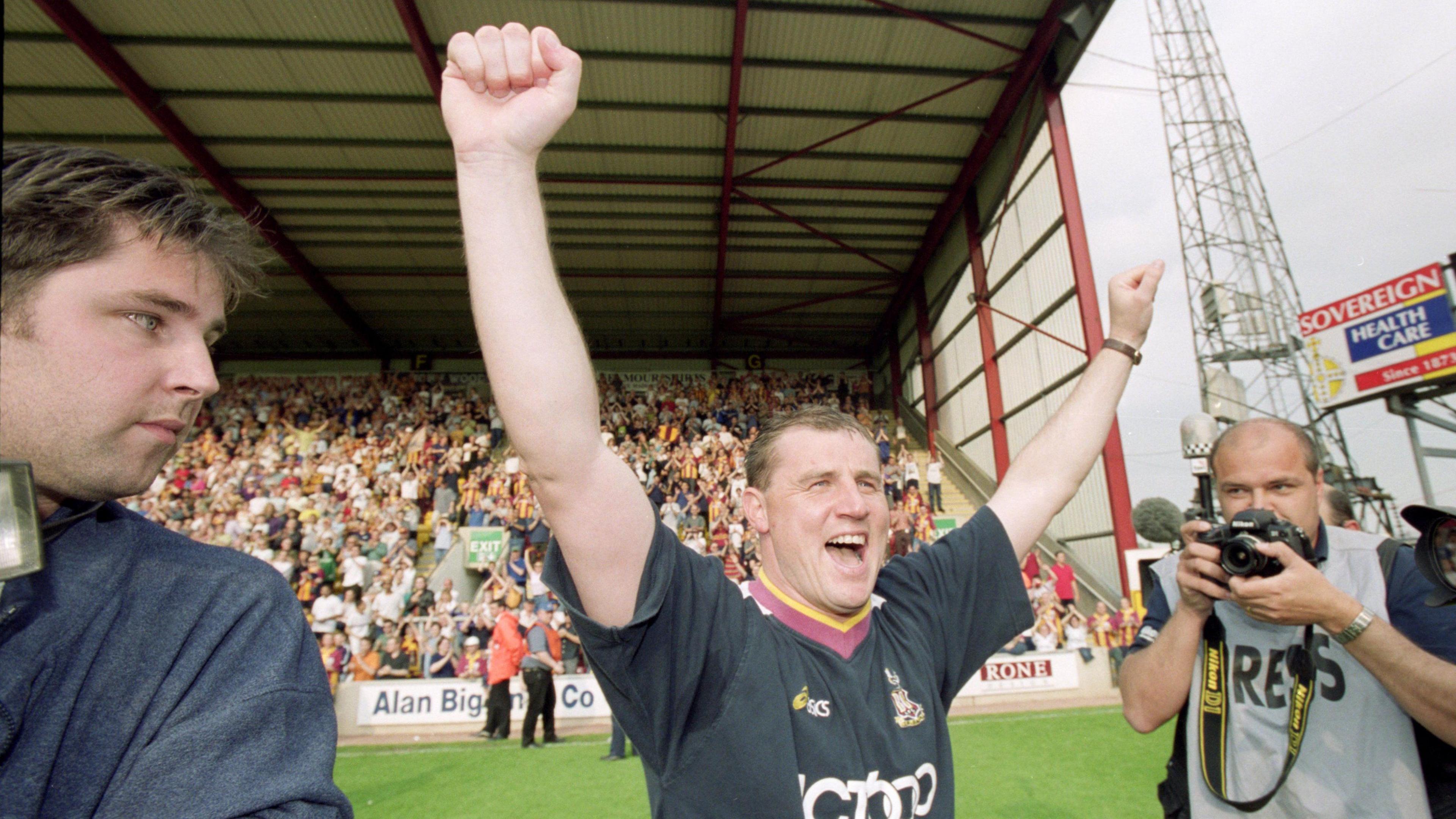 Paul Jewell with both arms aloft after leading Bradford to survival, flanked by a photographer on either side of him 