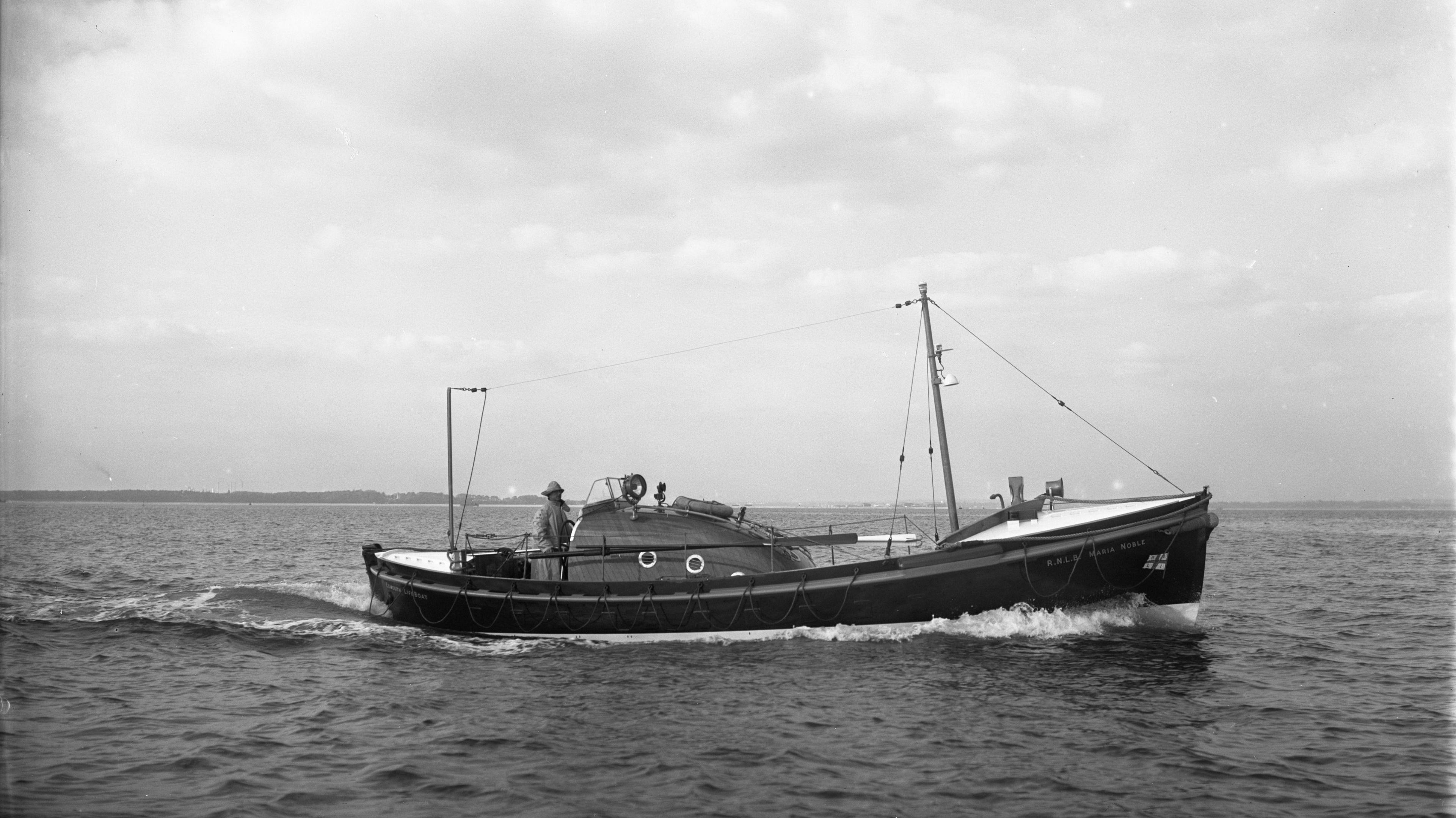 A black and white photo of an old lifeboat at sea.