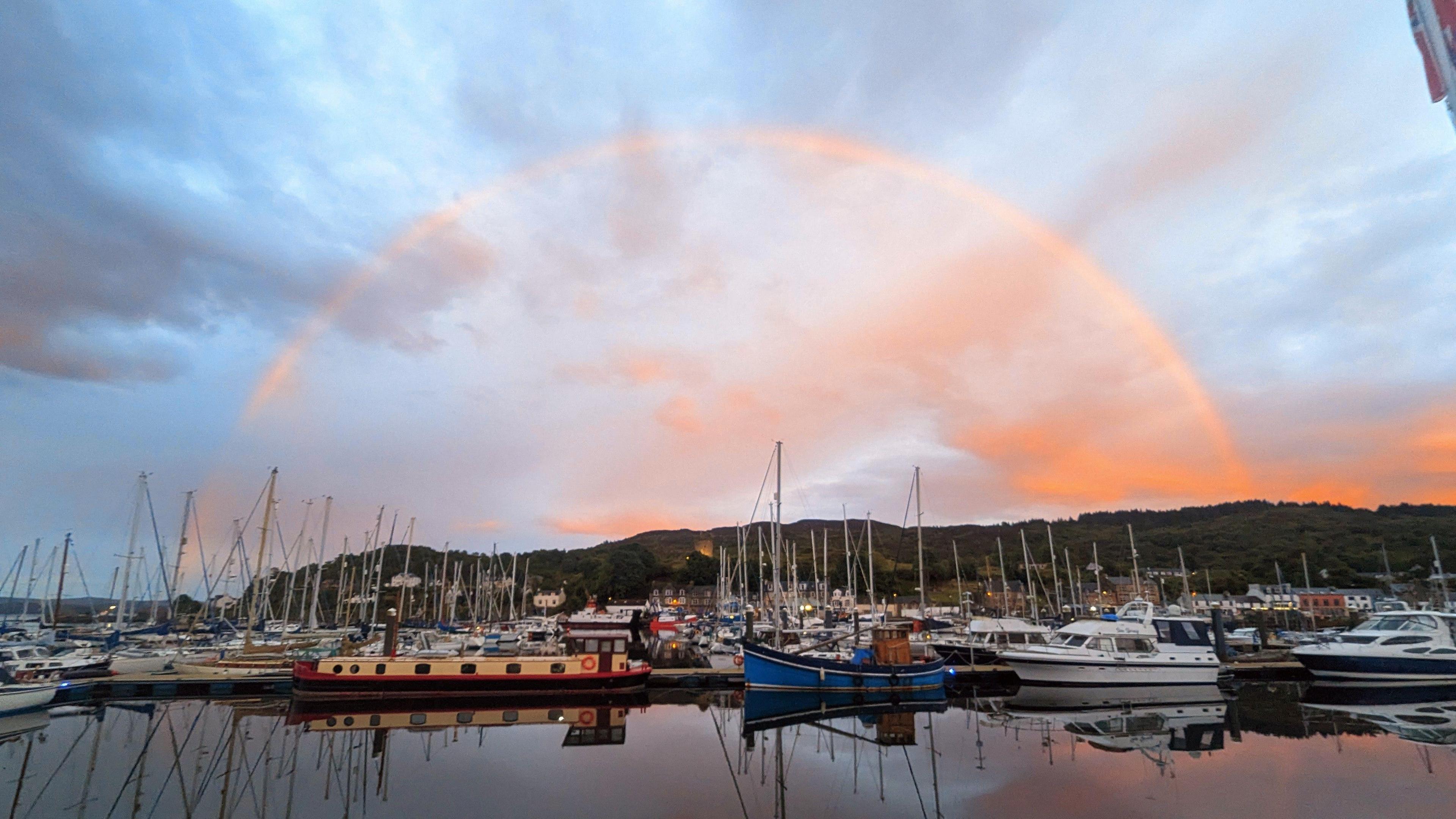 Rainbow sunset above boats on a loch