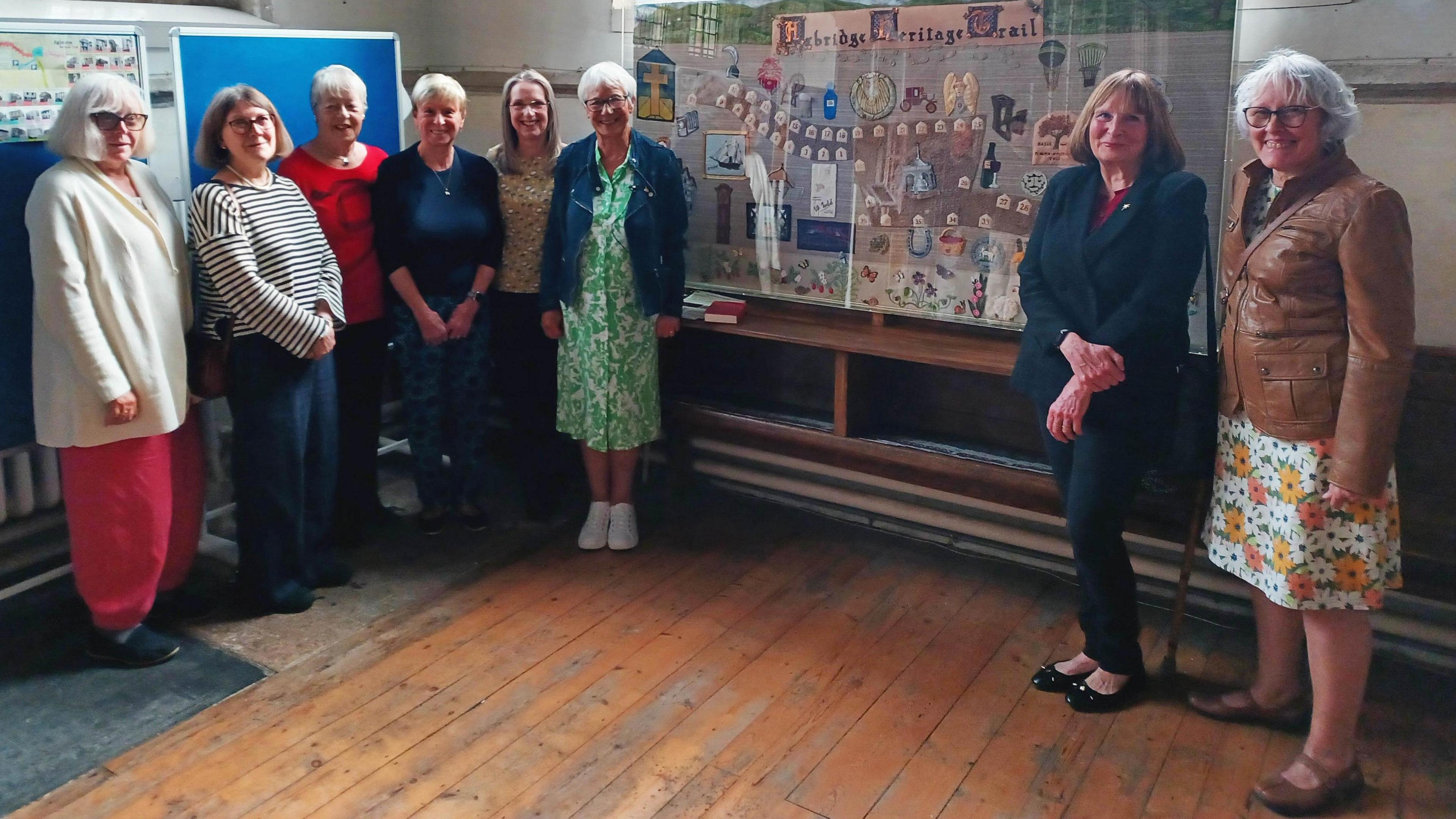 Eight women stand either side of a new tapestry in St John the Baptist Church in Axbridge in Somerset