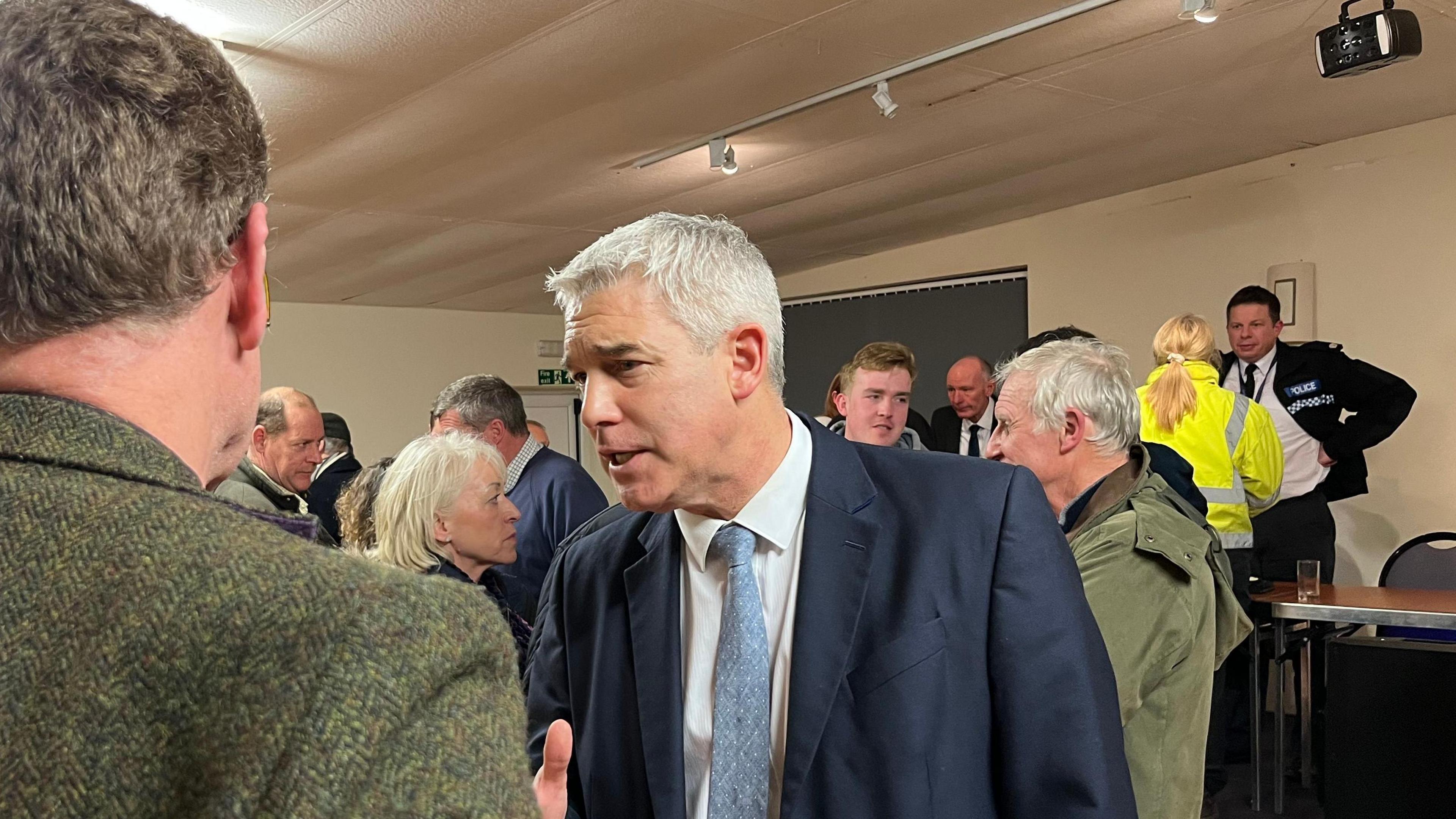 MP Steve Barclay with white hair talking to people in a room