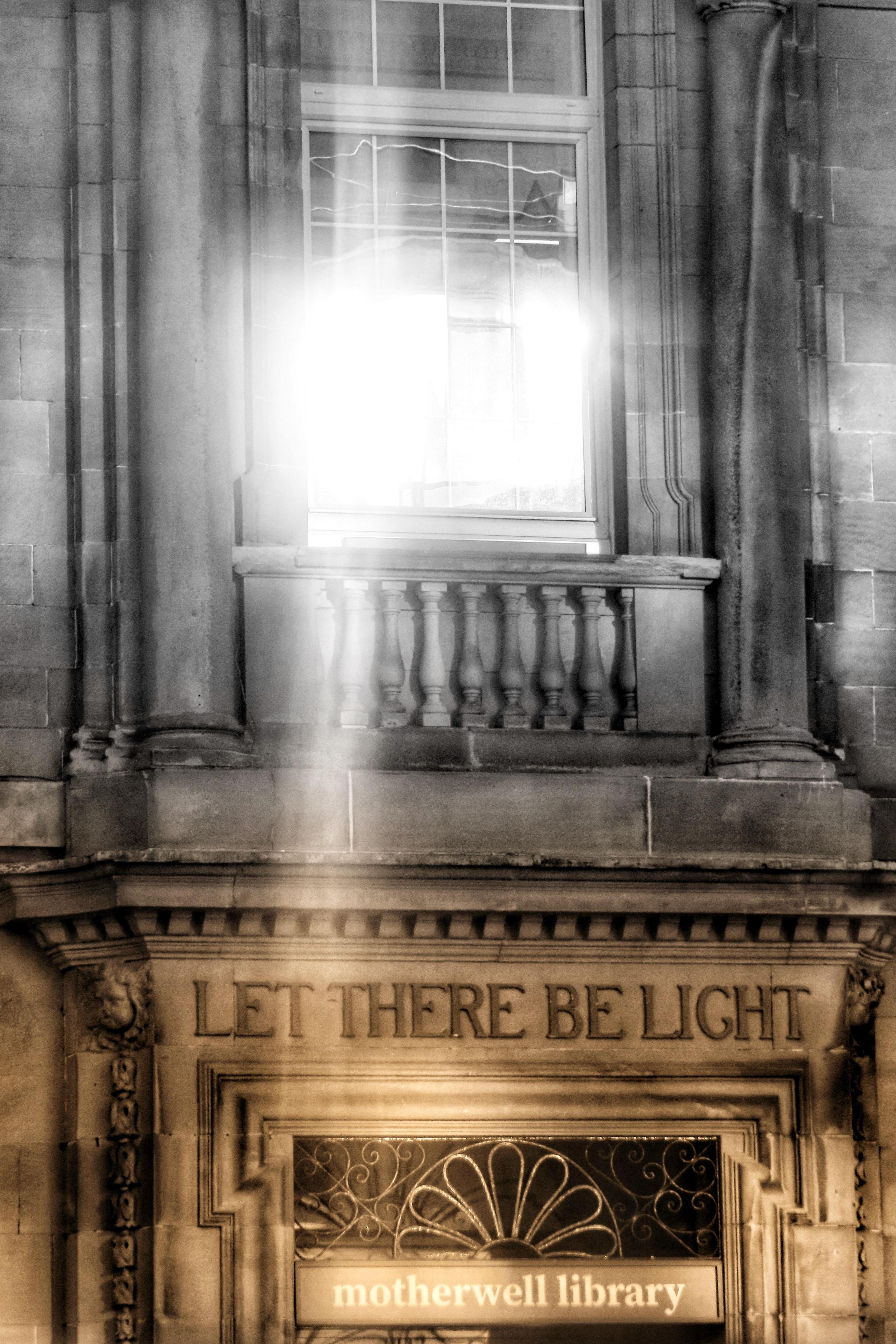 Light reflecting off window at Motherwell Library with Let There Be Light wording