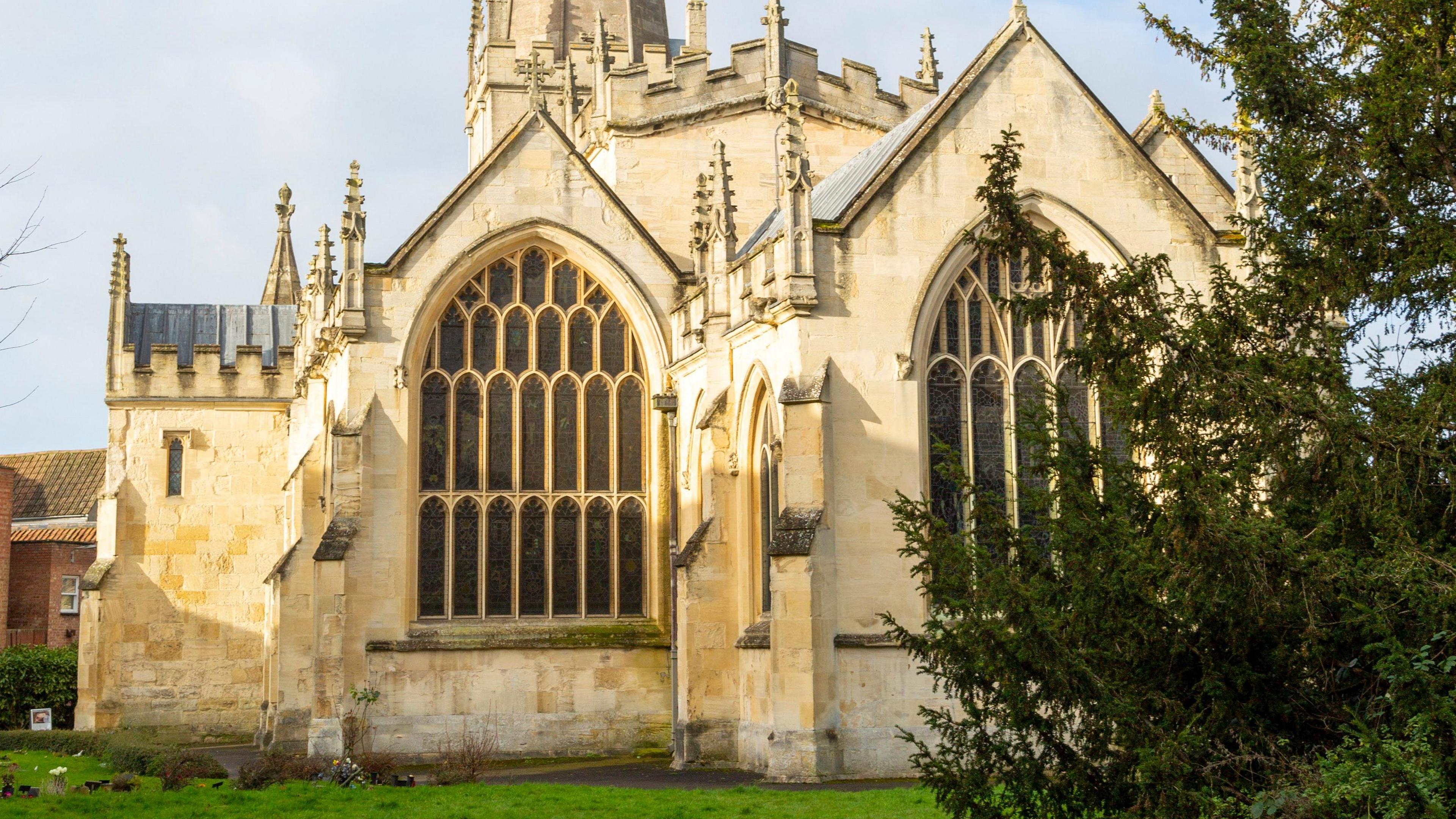 A 15-Century church with a tree in the foreground.