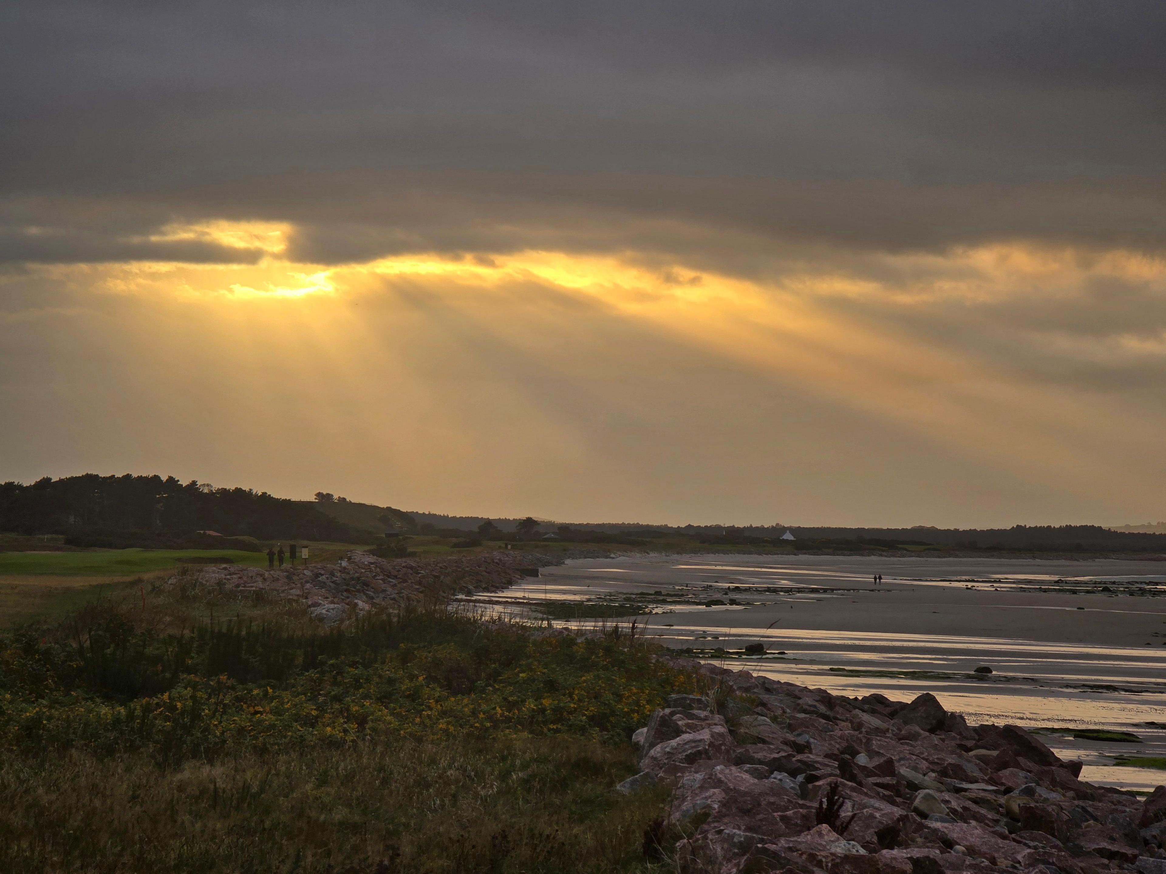 Landscape of a beach with sunlight peeking through grey clouds