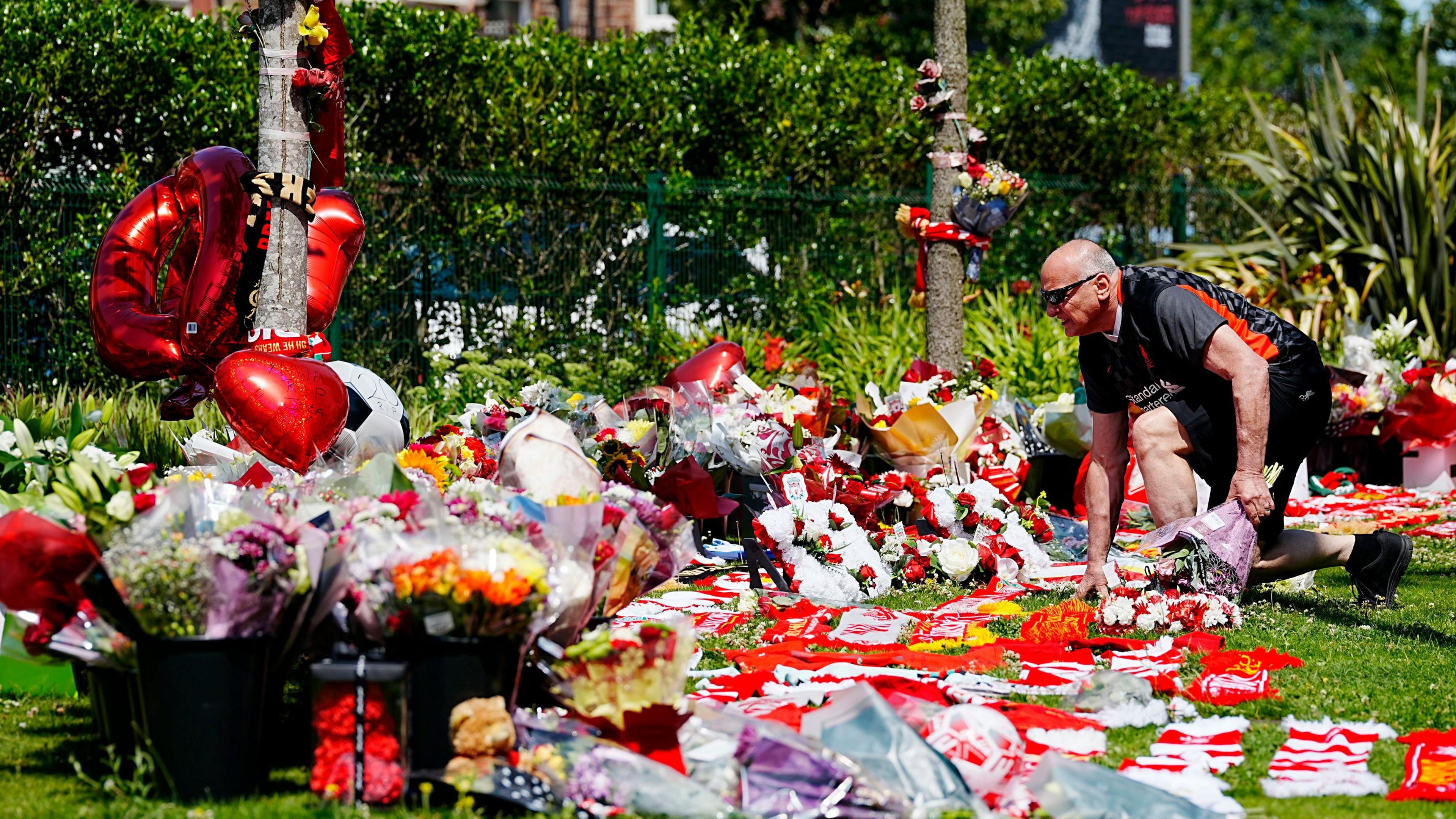 A Liverpool fan lays flowers outside Anfield following the death of Diogo Jota