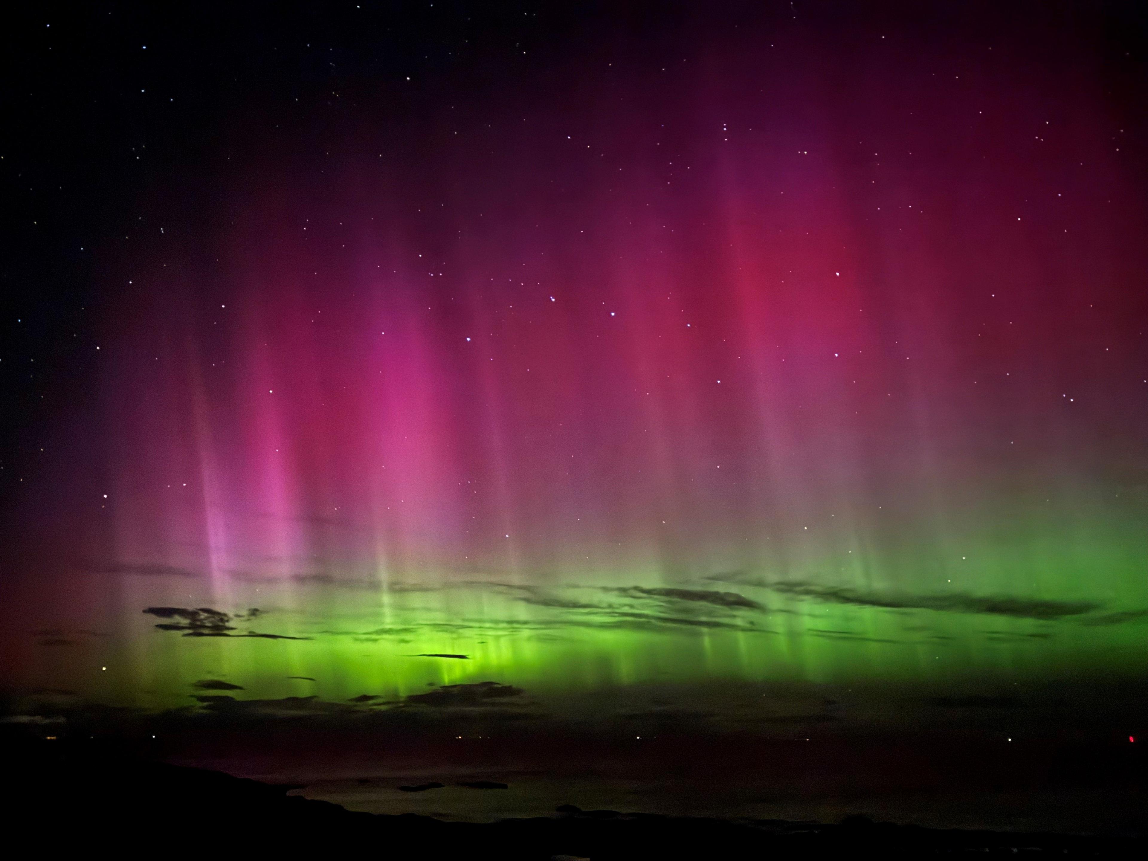 The aurora seen from across the Moray Firth at Hopeman. Clouds are illuminated by the display of colour.