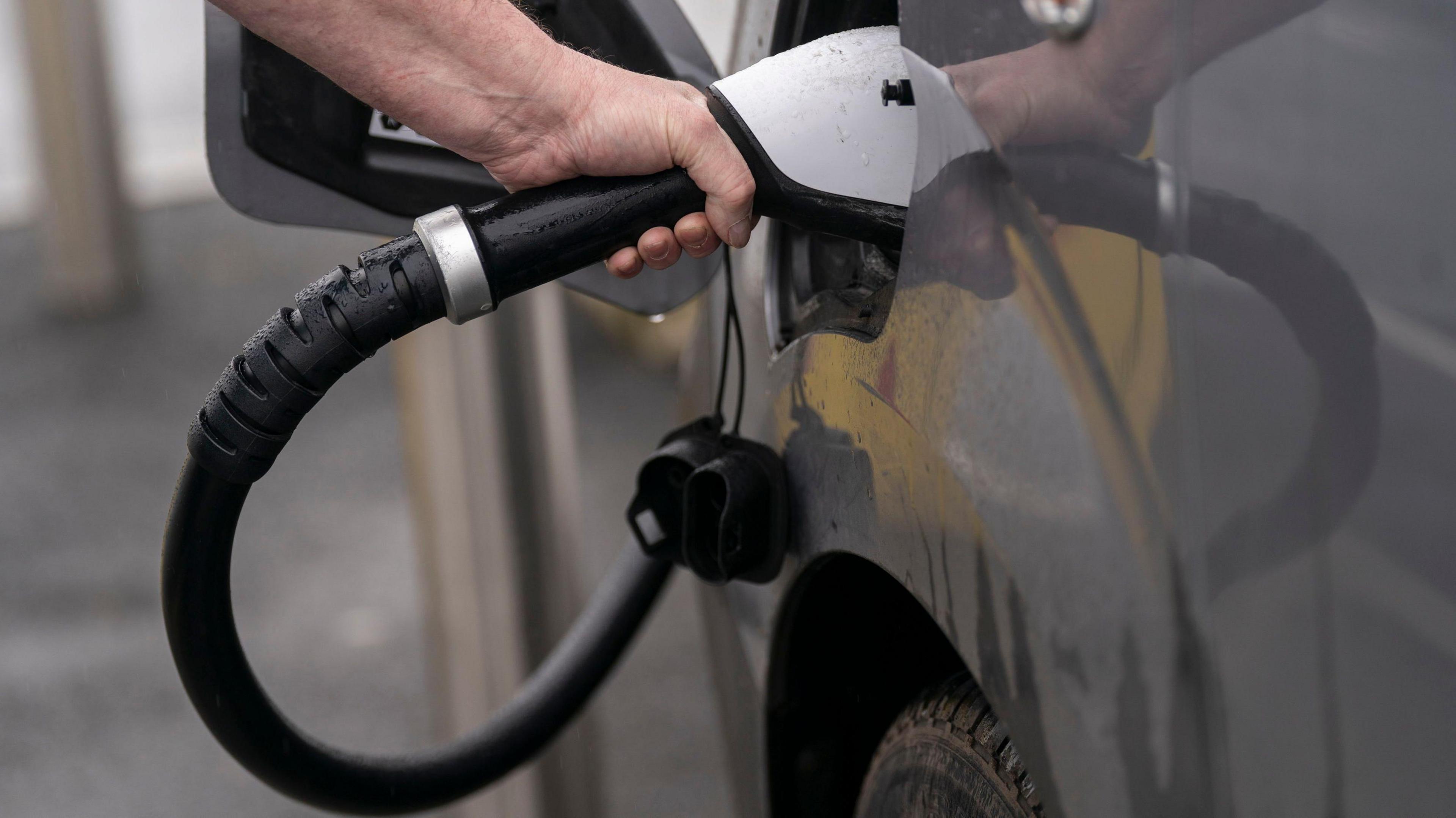 Person putting an electric charger into a vehicle