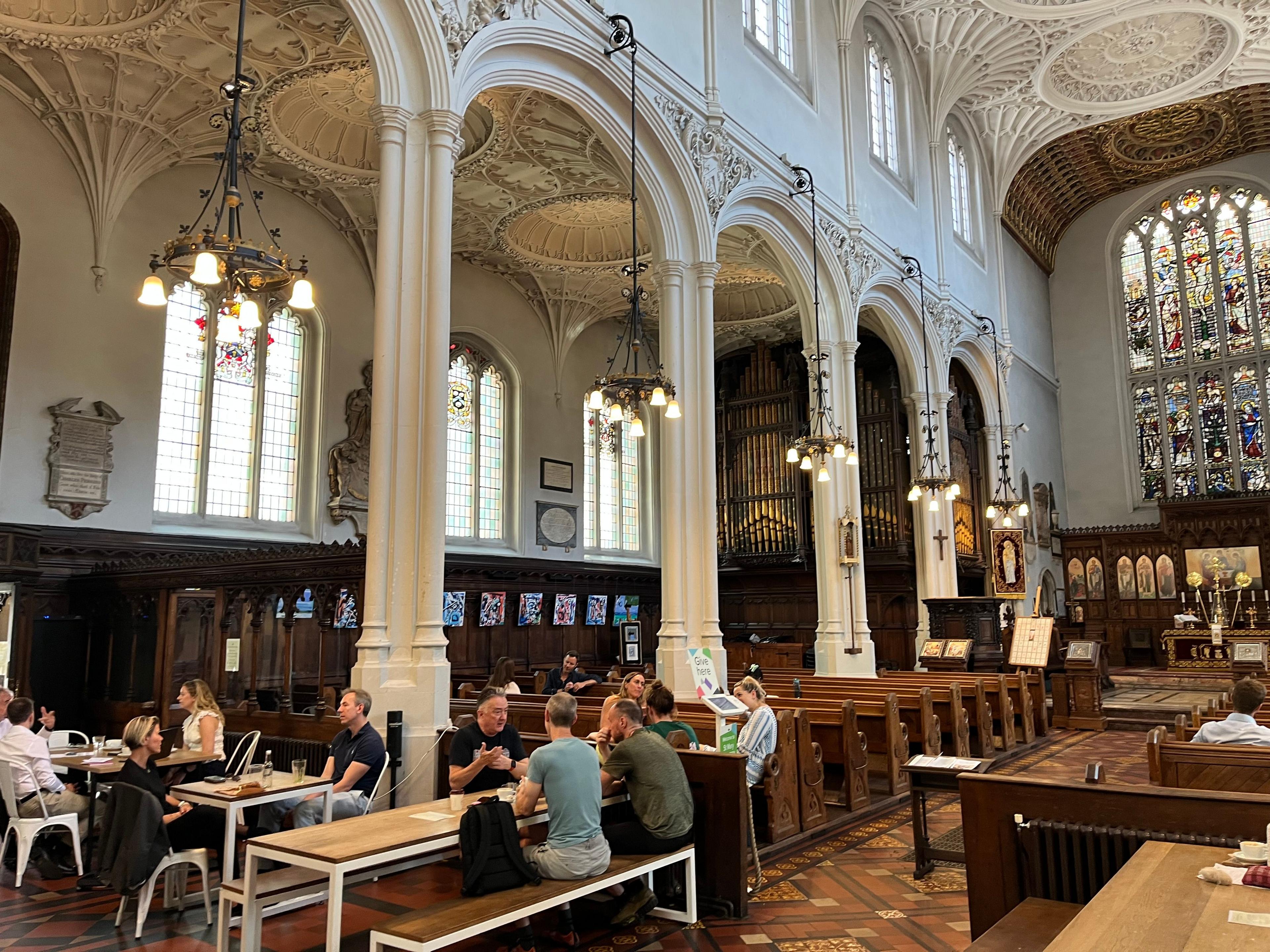 The interior of a church and people sitting, using it as a cafe space 