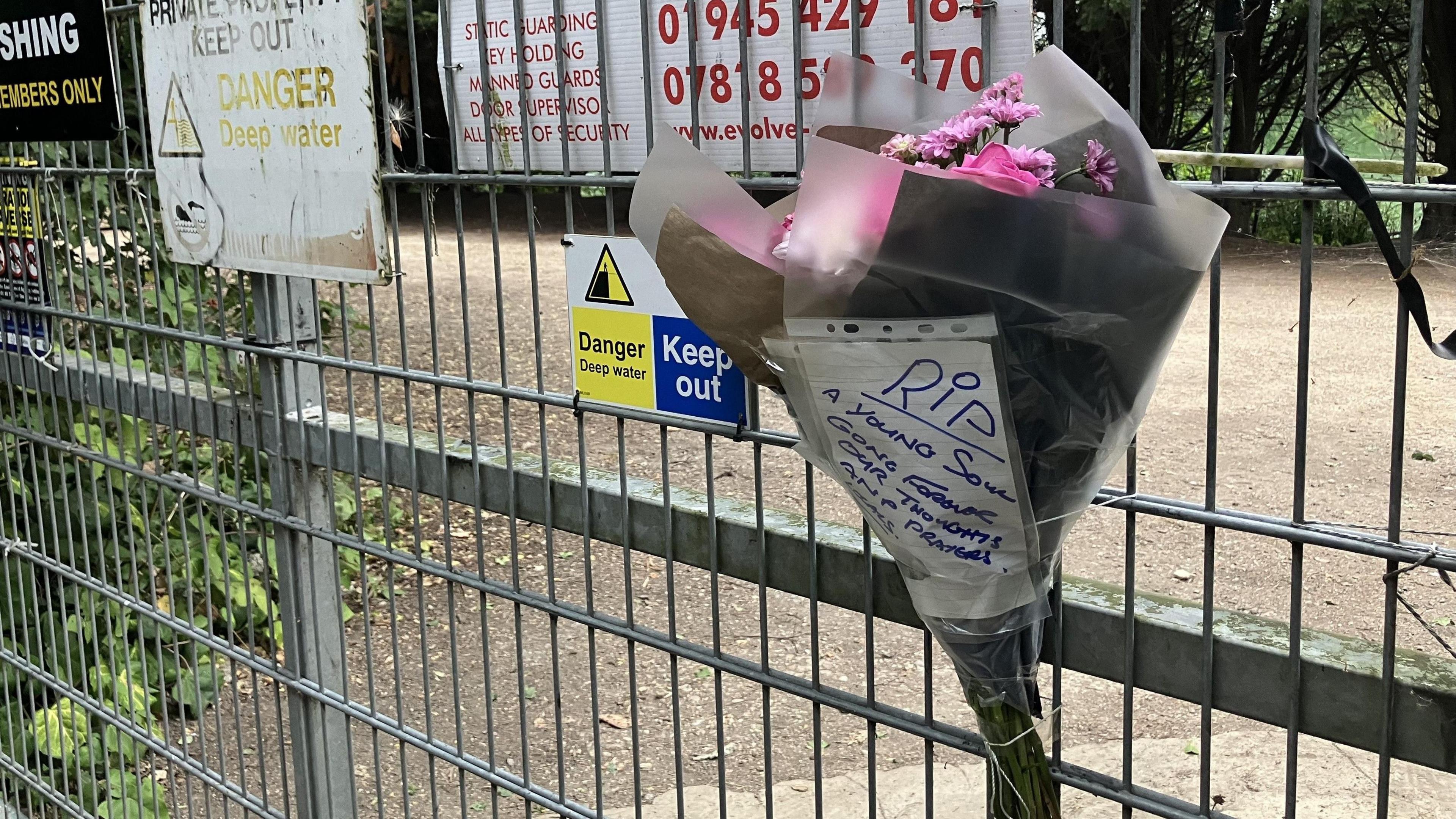 The floral tribute from local residents on a fence. A piece of paper attached the flowers reads: "RIP, a young soul, gone forever, our thoughts and prayers."