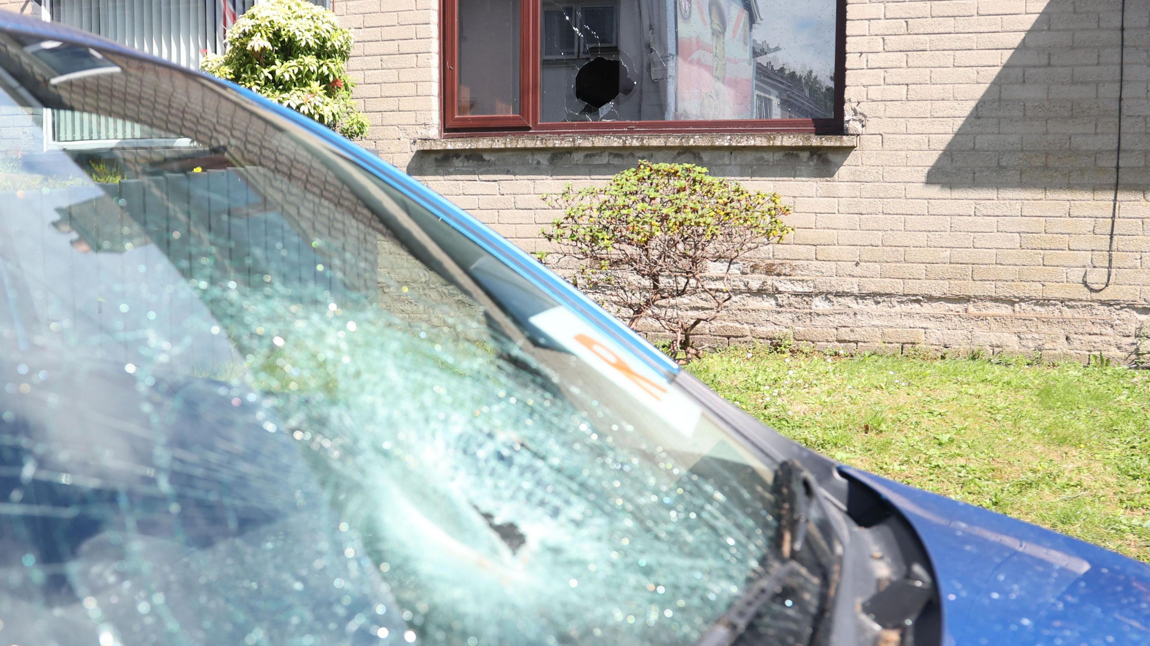 Smashed car window on blue car with R plates and smashed window of house living room