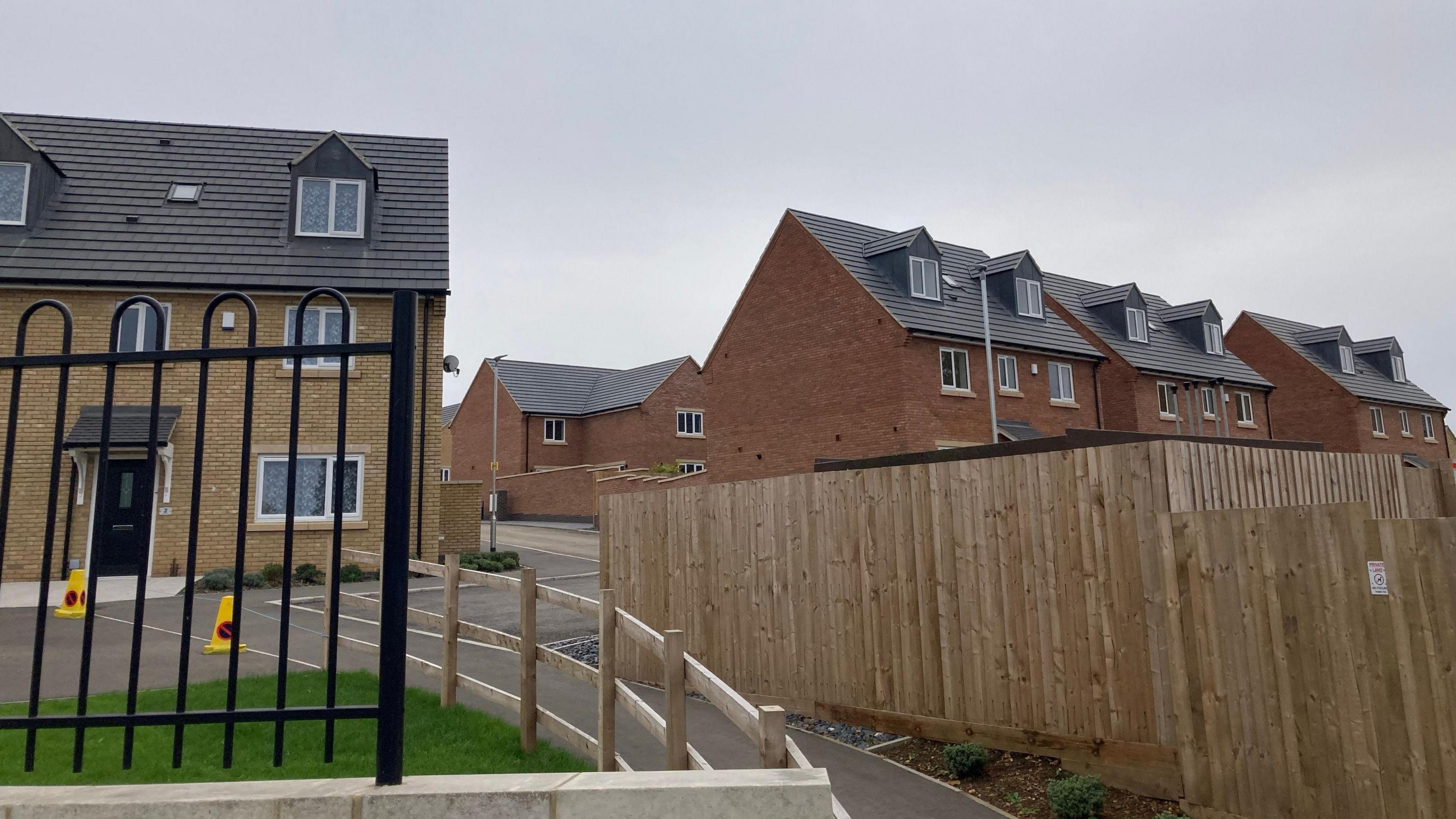 A street level view of the housing estate built on the former site of Rockingham Road showing a row of fencing and new build houses which are still under construction.