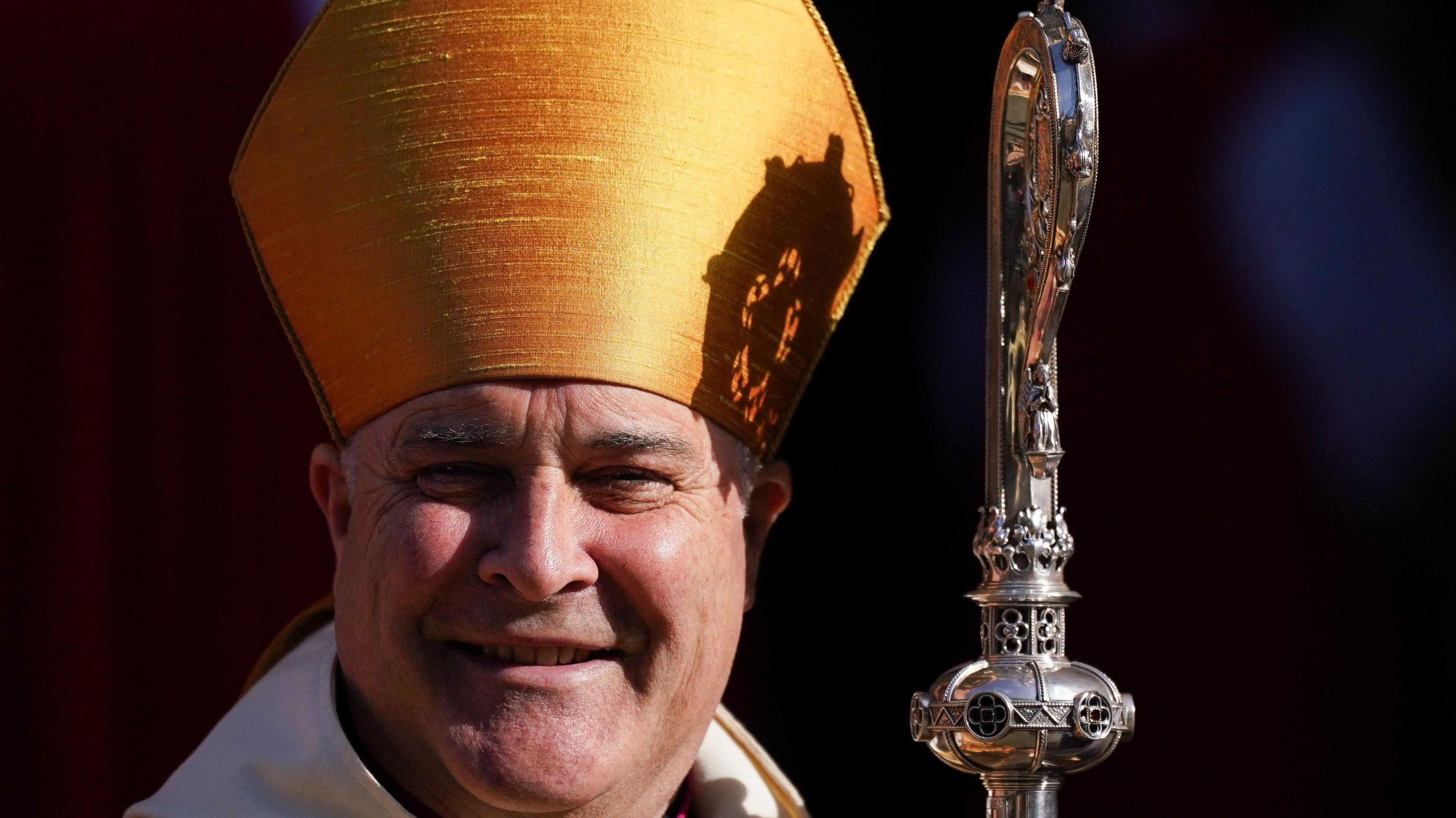 The Archbishop of York, smiling on a sunny day. He is wearing a bishop's mitre and is holding a crosier.