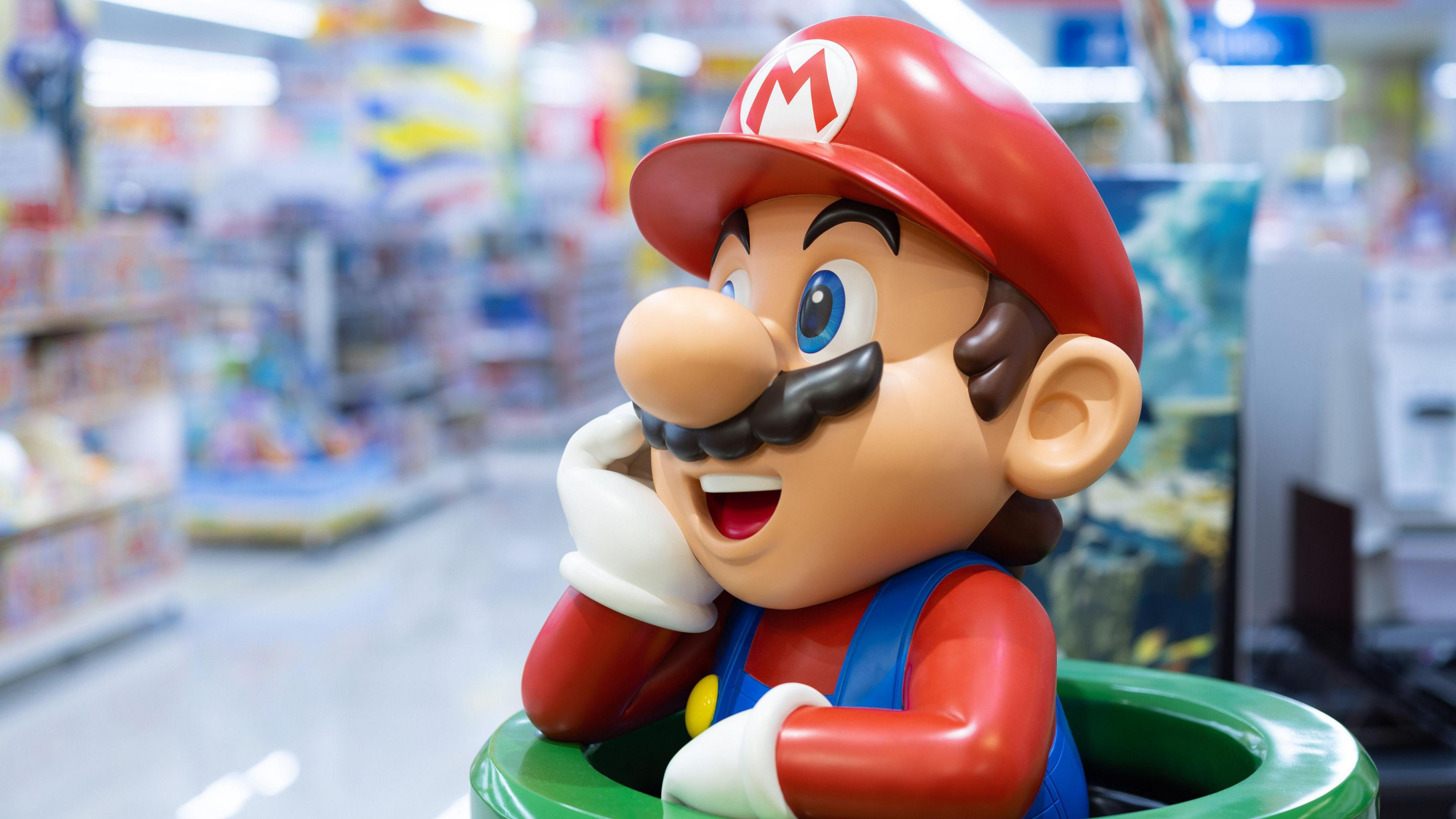 A statue of Super Mario, a character in dungarees with a hat and moustache, leaning out of a pipe in a shop
