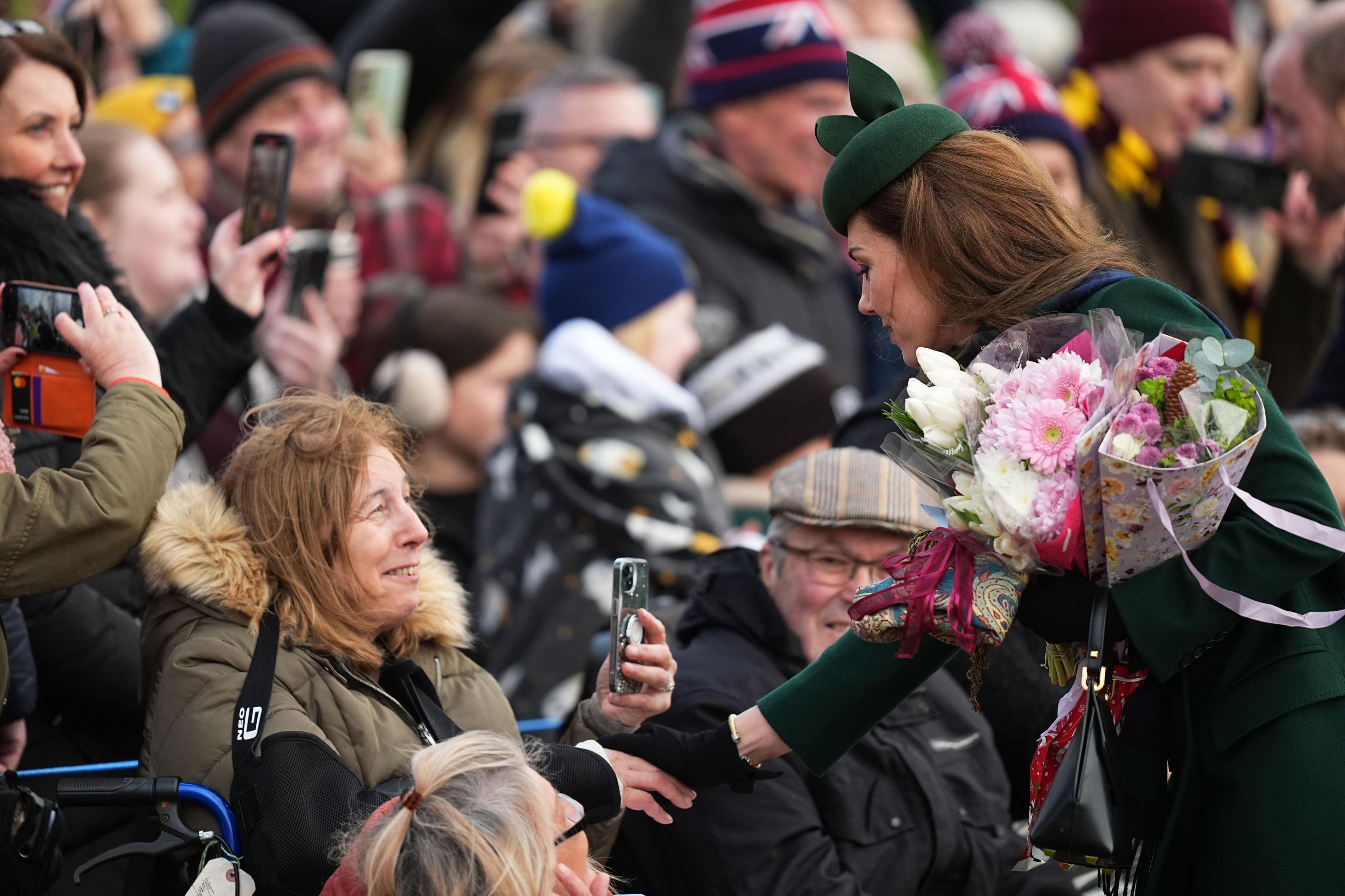 The Princess of Wales wearing a green coat and matching hat holding two bouquets of flowets speaking to a wellwisher following the Christmas Day morning church service at St Mary Magdalene Church in Sandringham, Norfolk. 