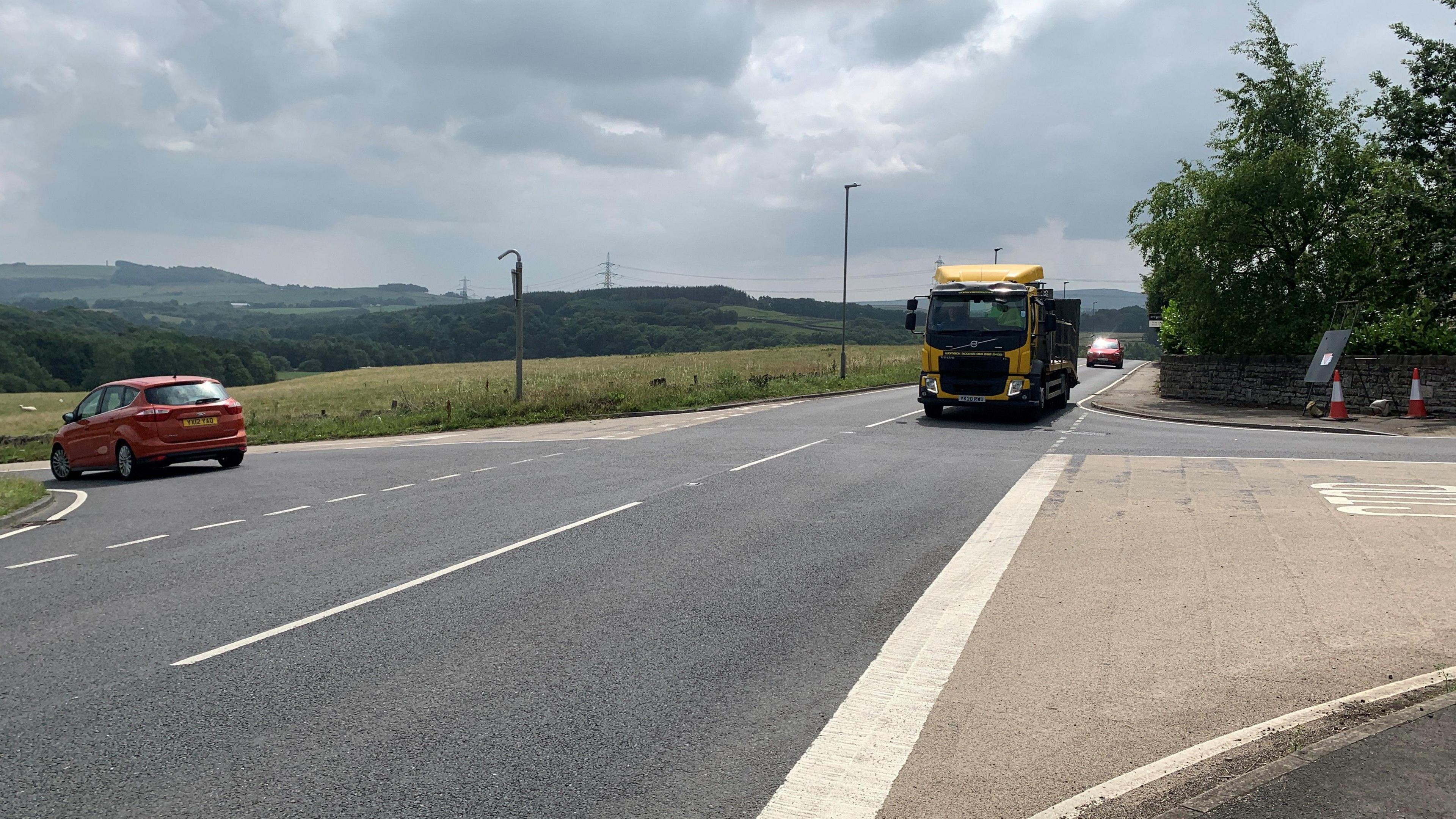 Hazlehead Crossroads on the A616. It is a rural area. A red car turns left as a yellow HGV approaches the junction.