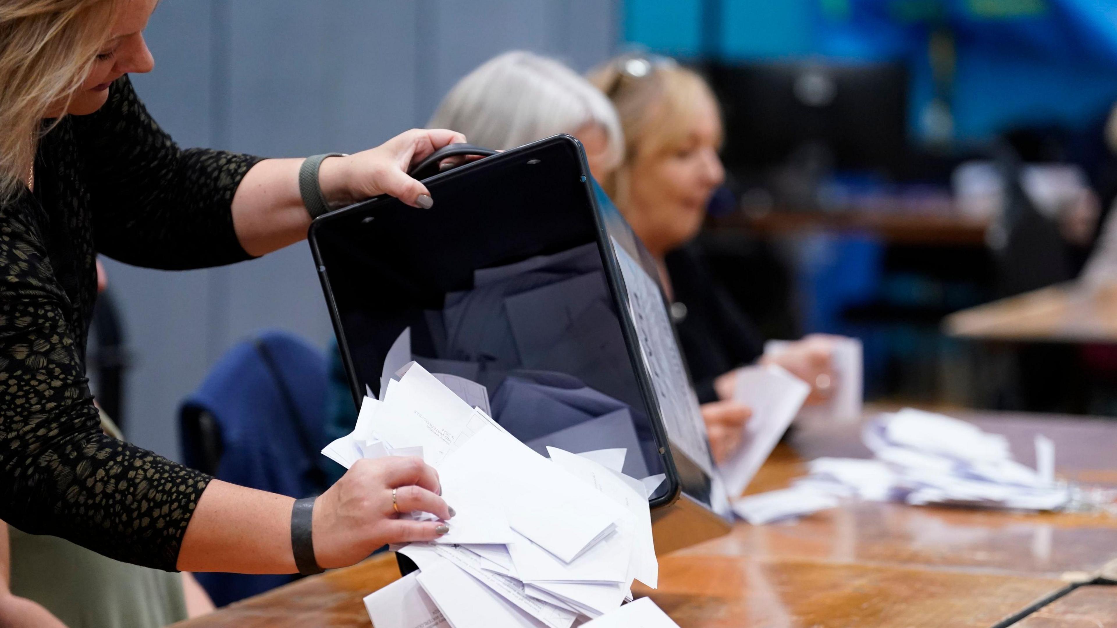 A woman emptying ballot papers on to a desk to be counted during an election