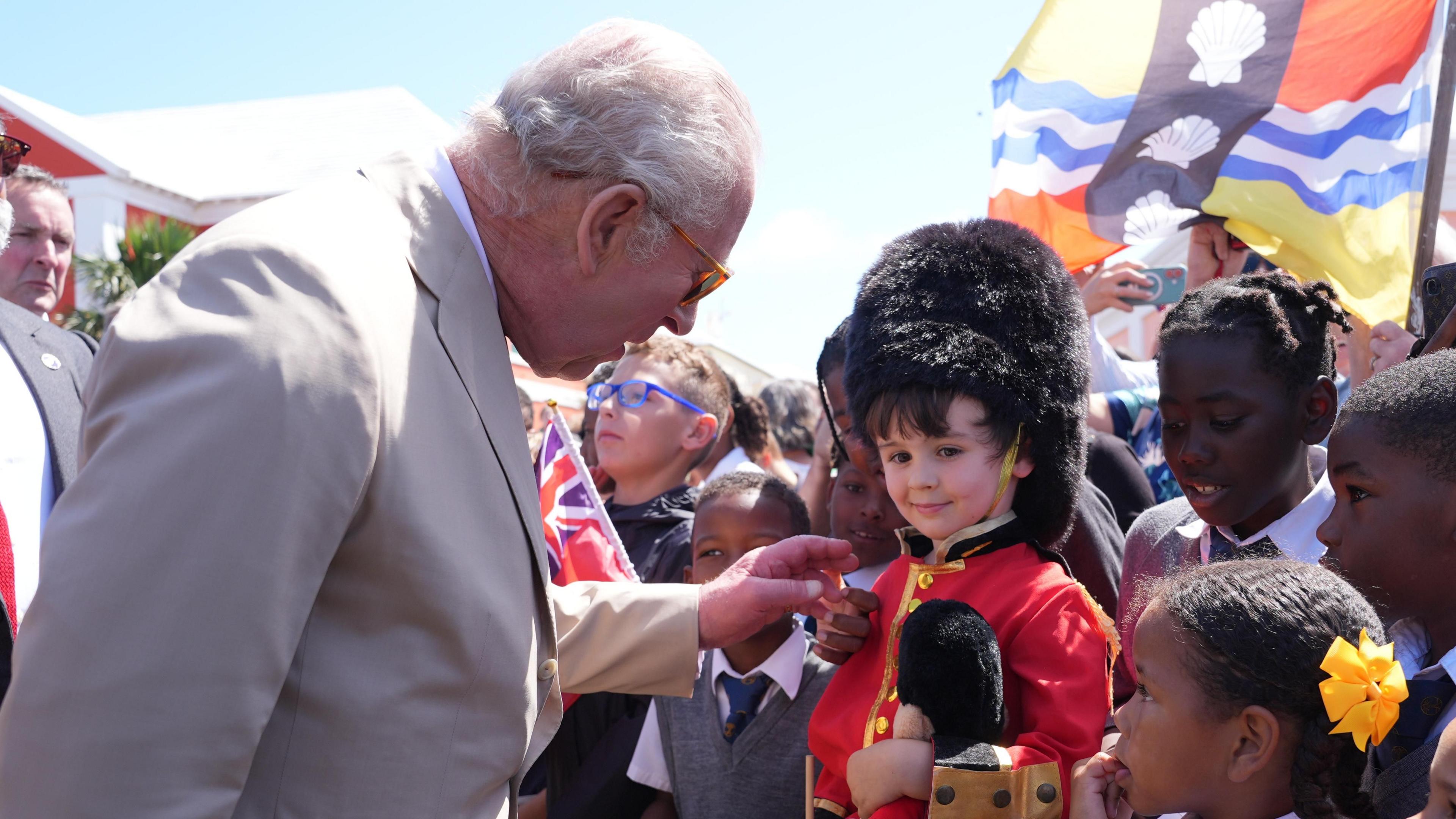 Mbreti Çarlsi III i flet një djali të vogël me uniformë roje. Djali i vogël ka veshur një arush pelushi që gjithashtu mban të njëjtën uniformë.