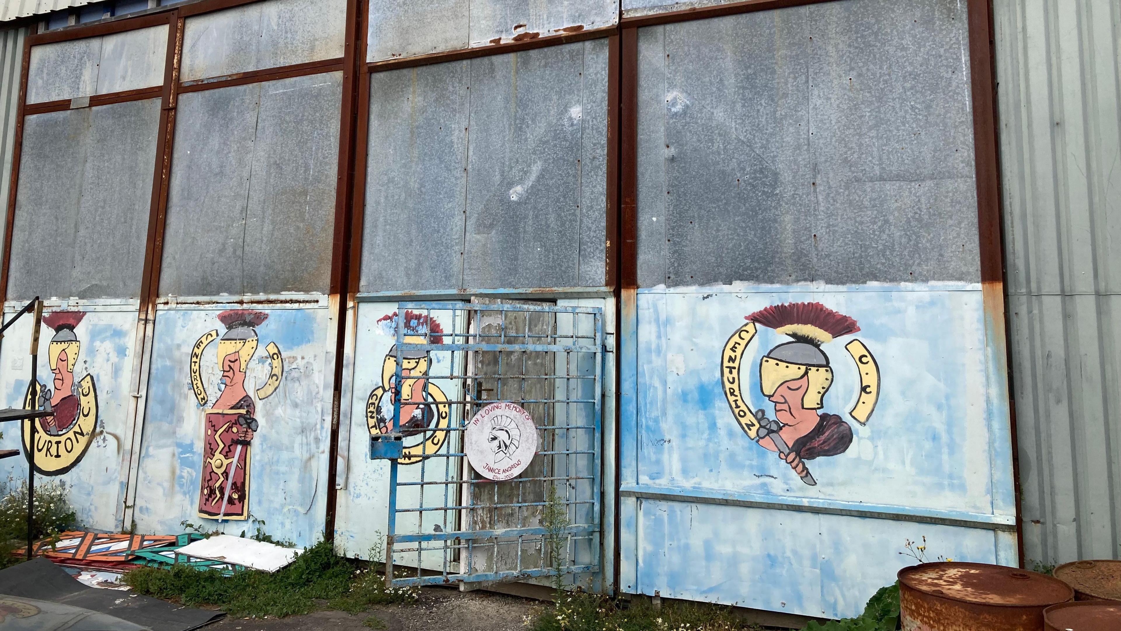 One of the carnival sheds from the outside. It is built out of different metal sheets and is decorated with a carnival club logo.