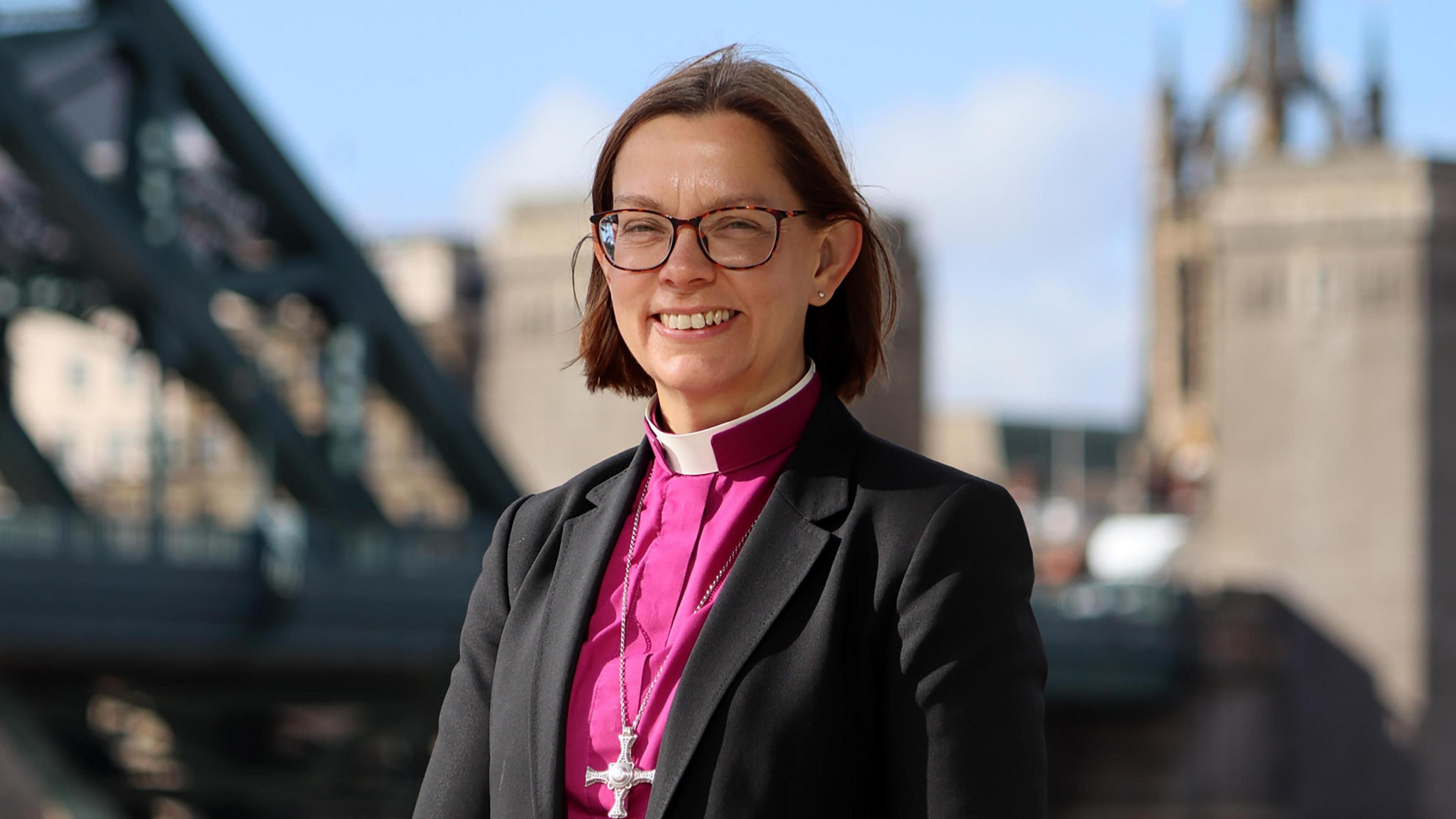 Bishop of Newcastle Helen-Ann Hartley wears a pink robe and brown glasses