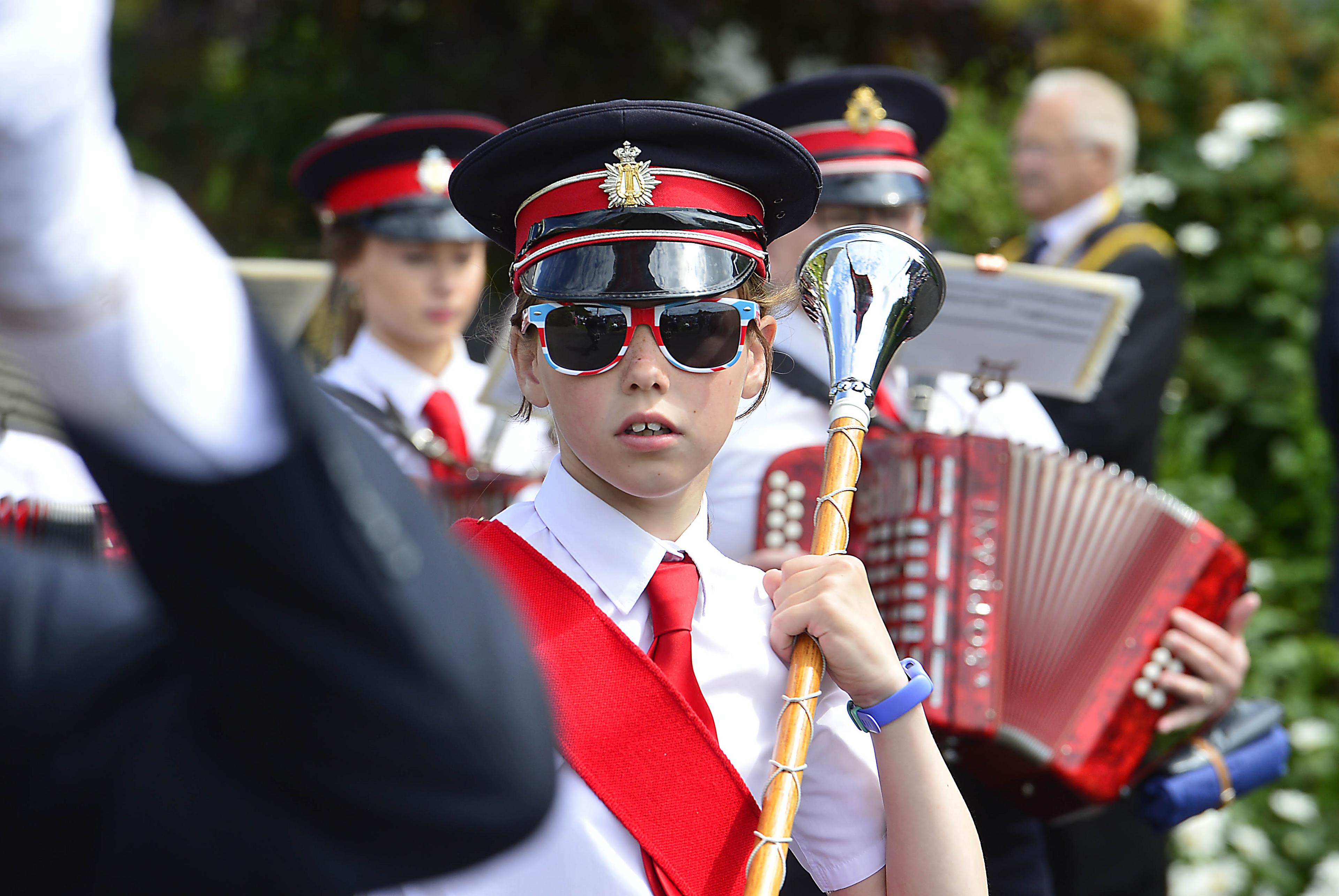 A child in union flag sunglasses marches with a baton